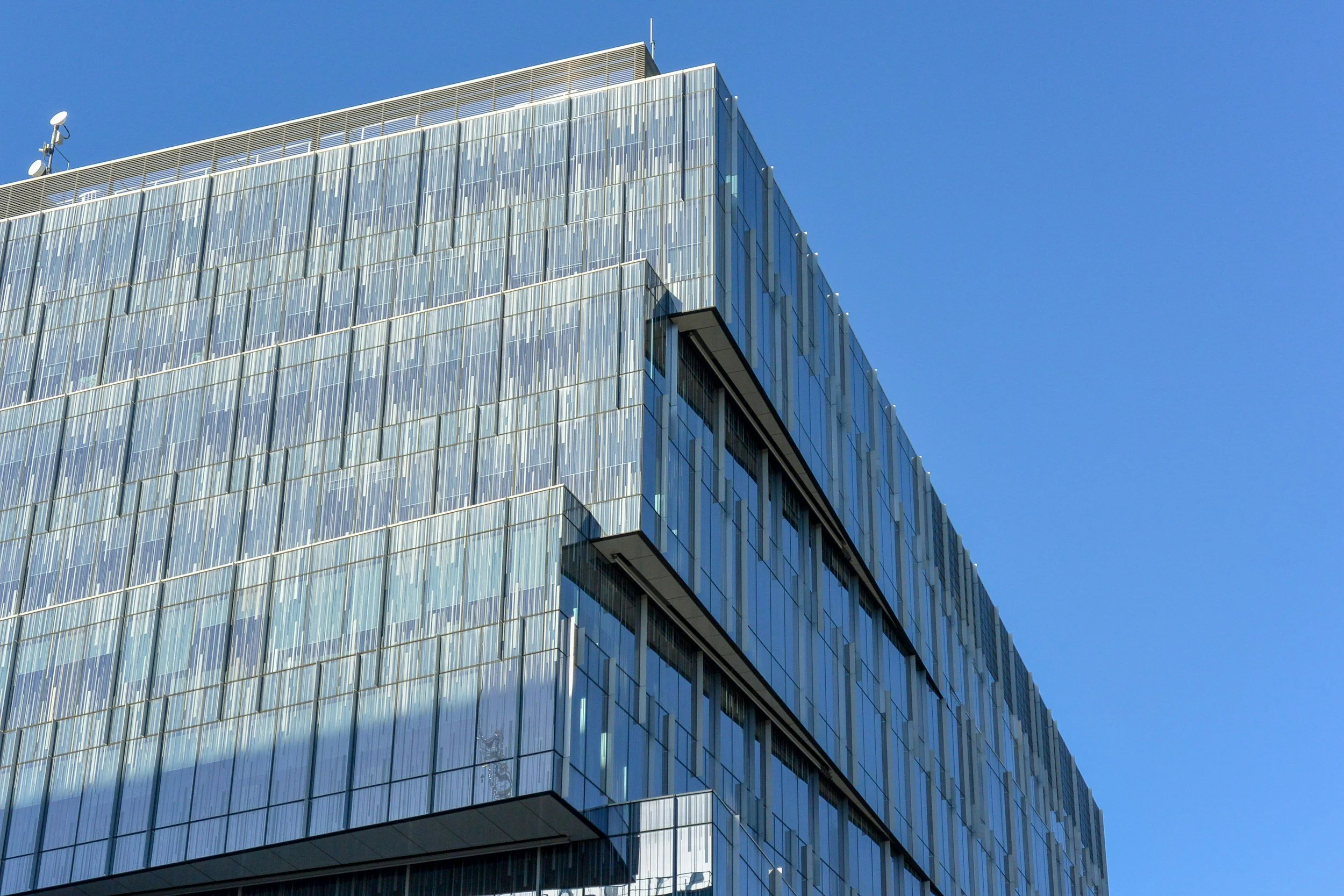Modern glass office building with blue sky in the background.