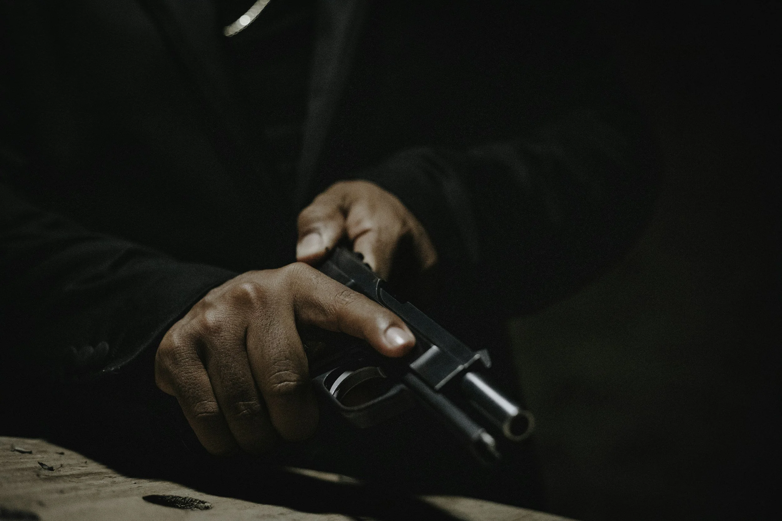 Person holding a handgun in a dark setting.