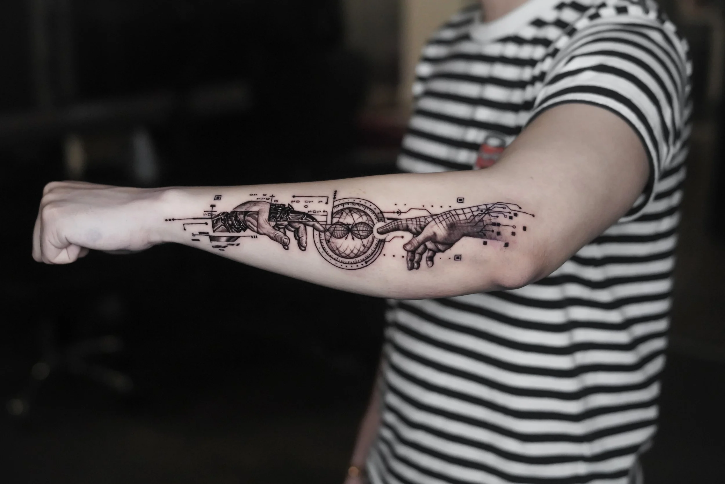 Tattoo of Michelangelo's Creation of Adam on a person's forearm, depicting two hands reaching toward each other with digital art elements.
