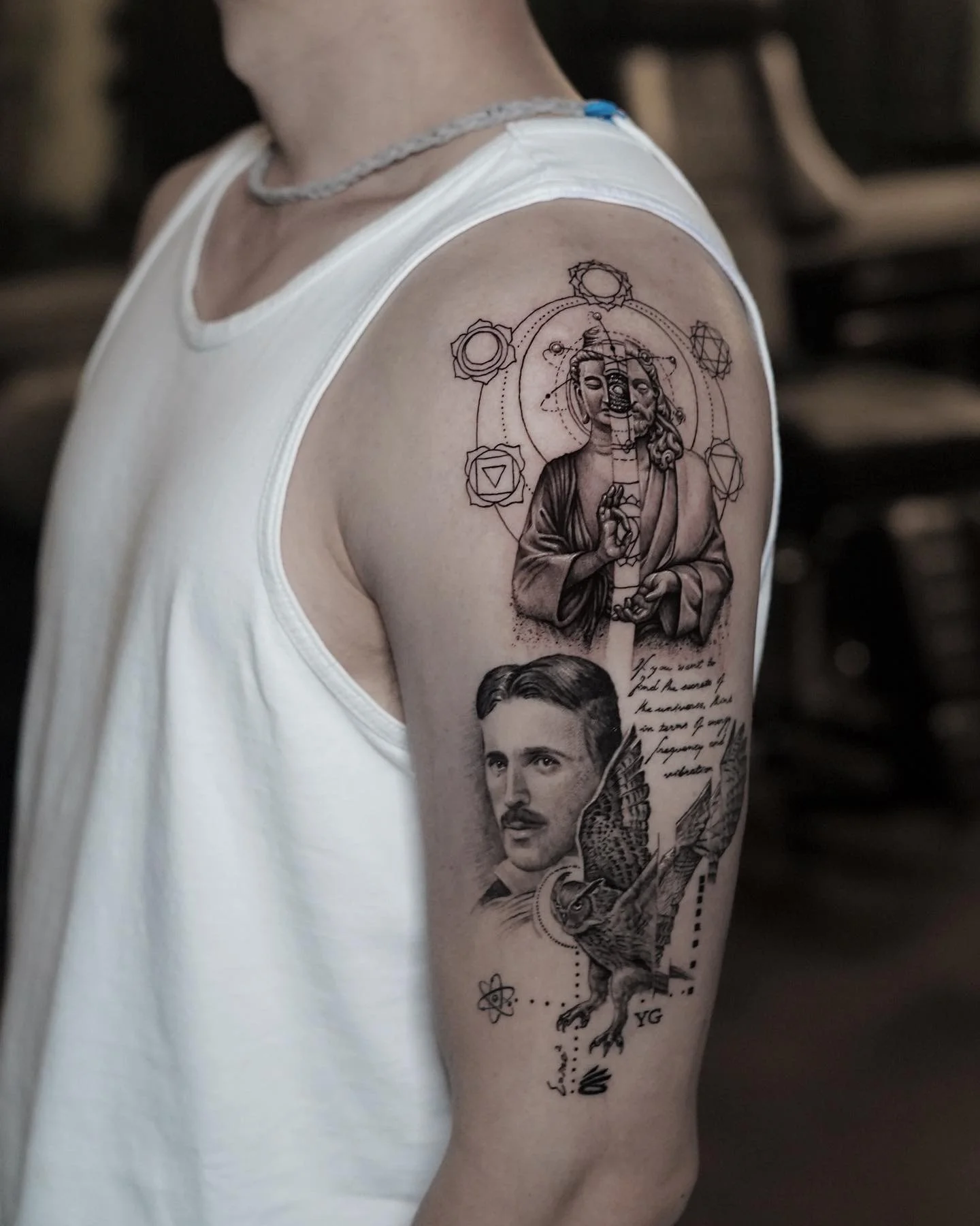 Black and gray tattoo sleeve on a person's upper arm, featuring a religious figure with a halo, a portrait of a man with a mustache, a flying bird with a key, scientific symbols, and handwritten text.