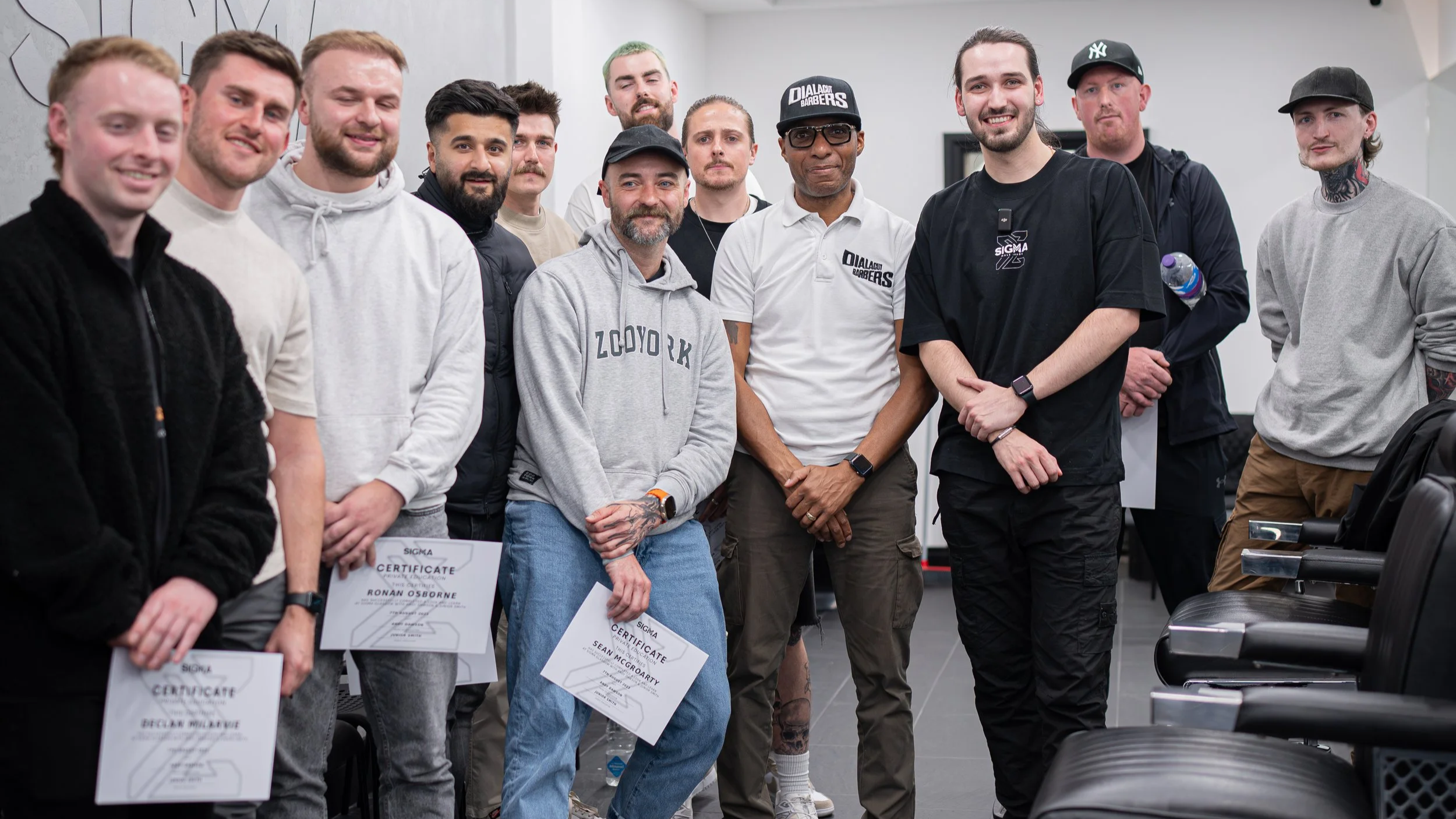 Group of men posing for a photo, some holding certificates, in an indoor setting.