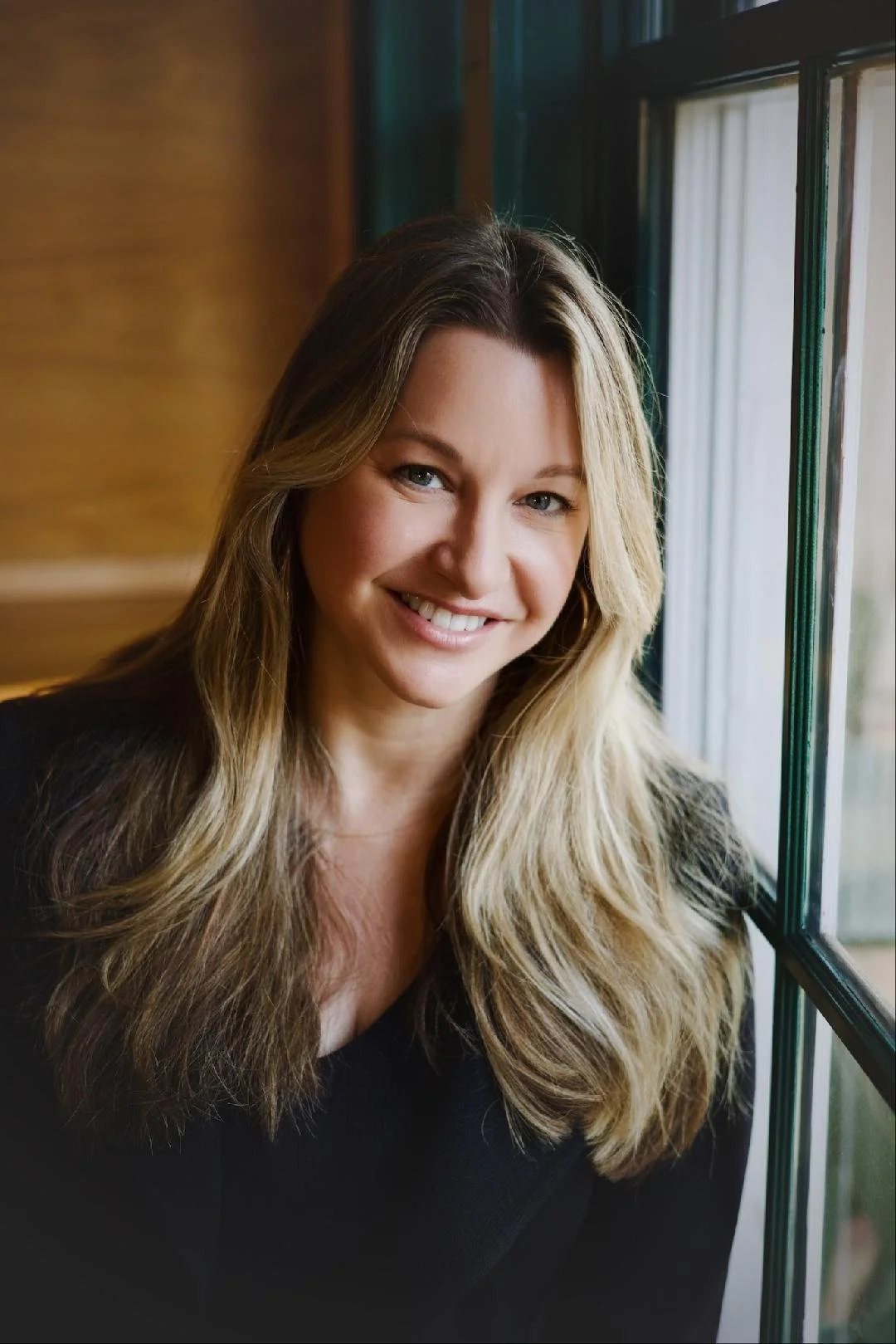 Headshot of a blonde woman in a black sweater. It is Martha Shade, the executive producer.