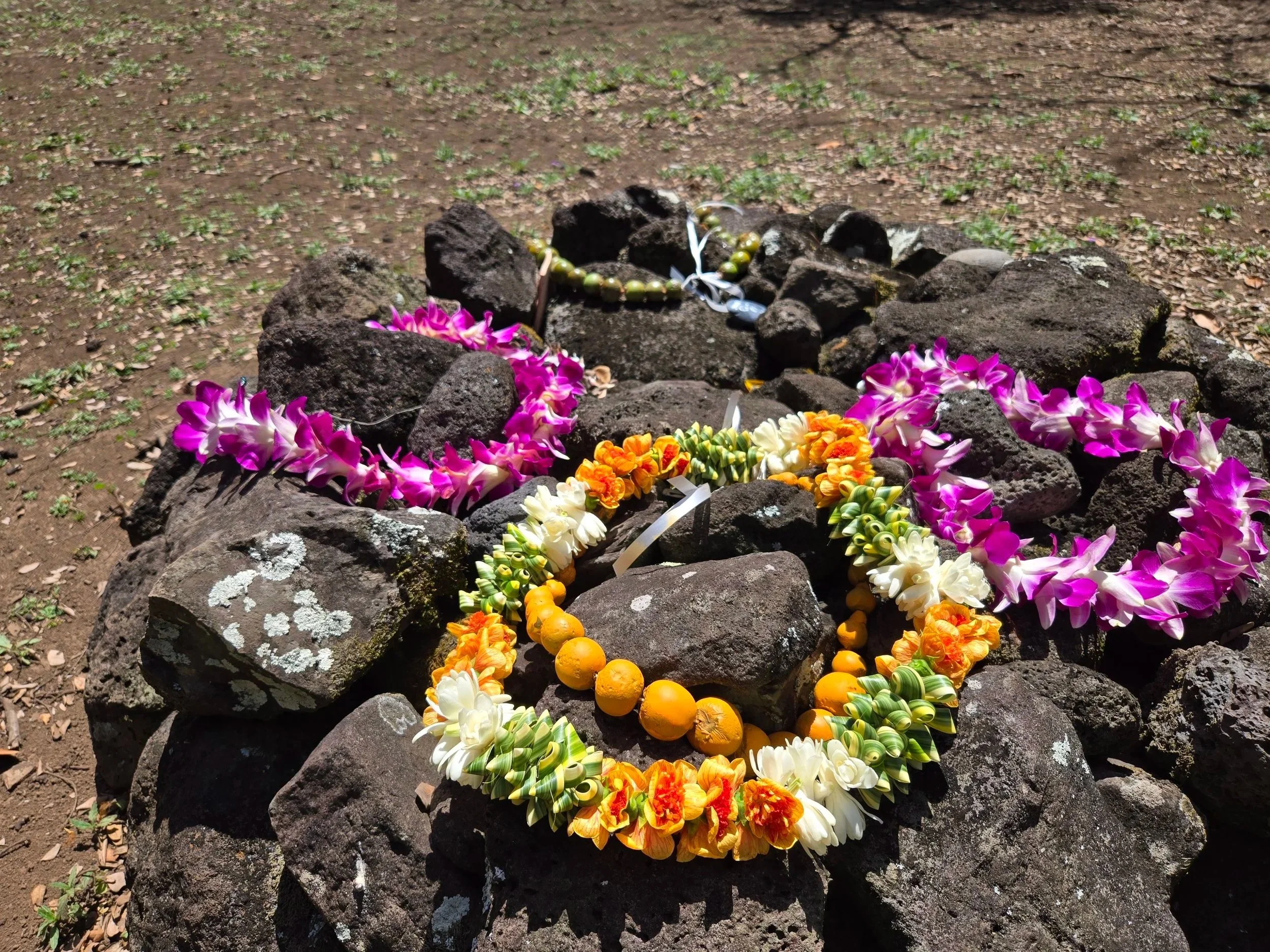 An ahu, or memorial site, made up of rocks decorated with colorful flower lei and necklaces.