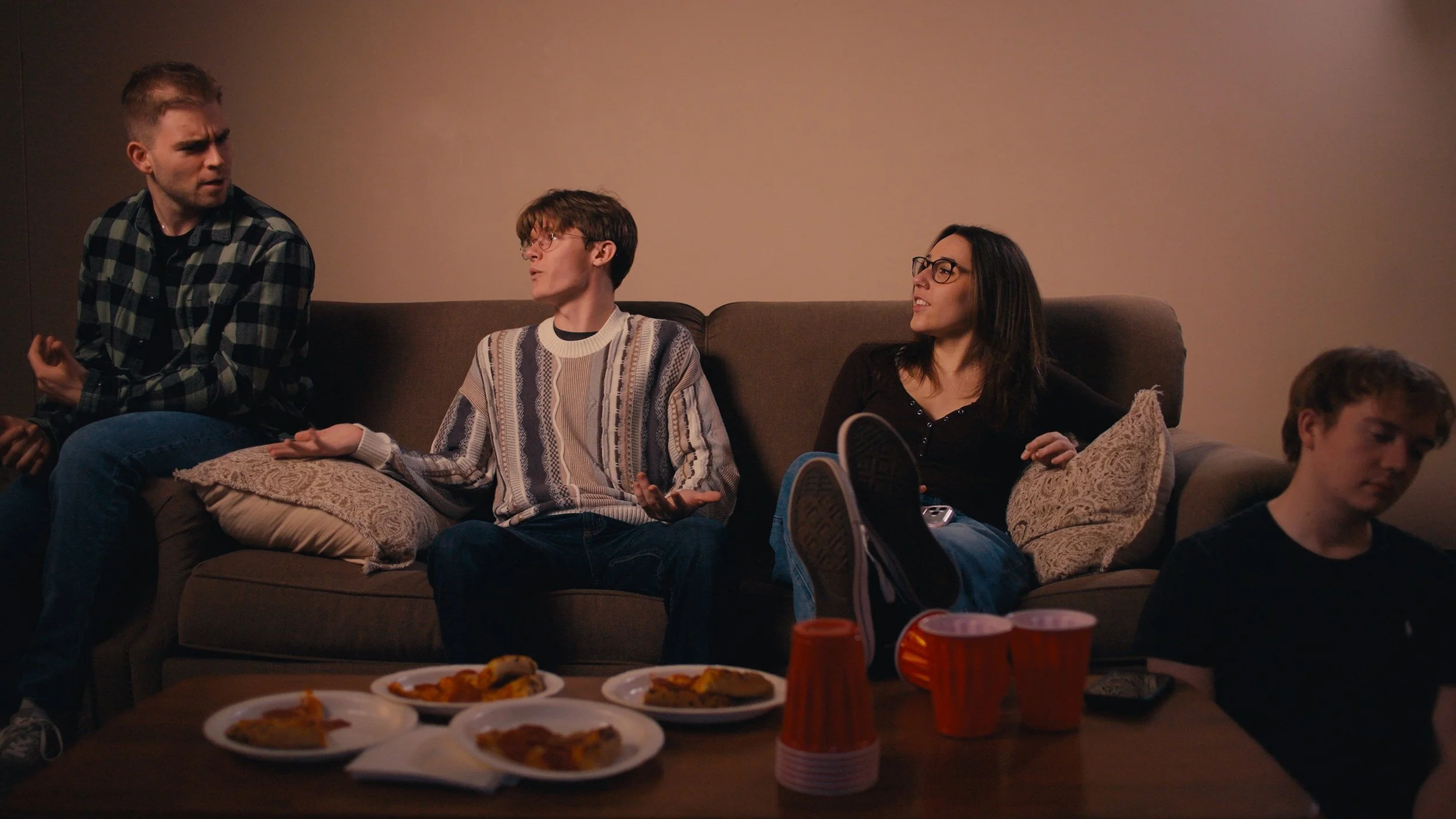 The group of friends; Graham, Nolan, Jane, and Alex talking in the living room.