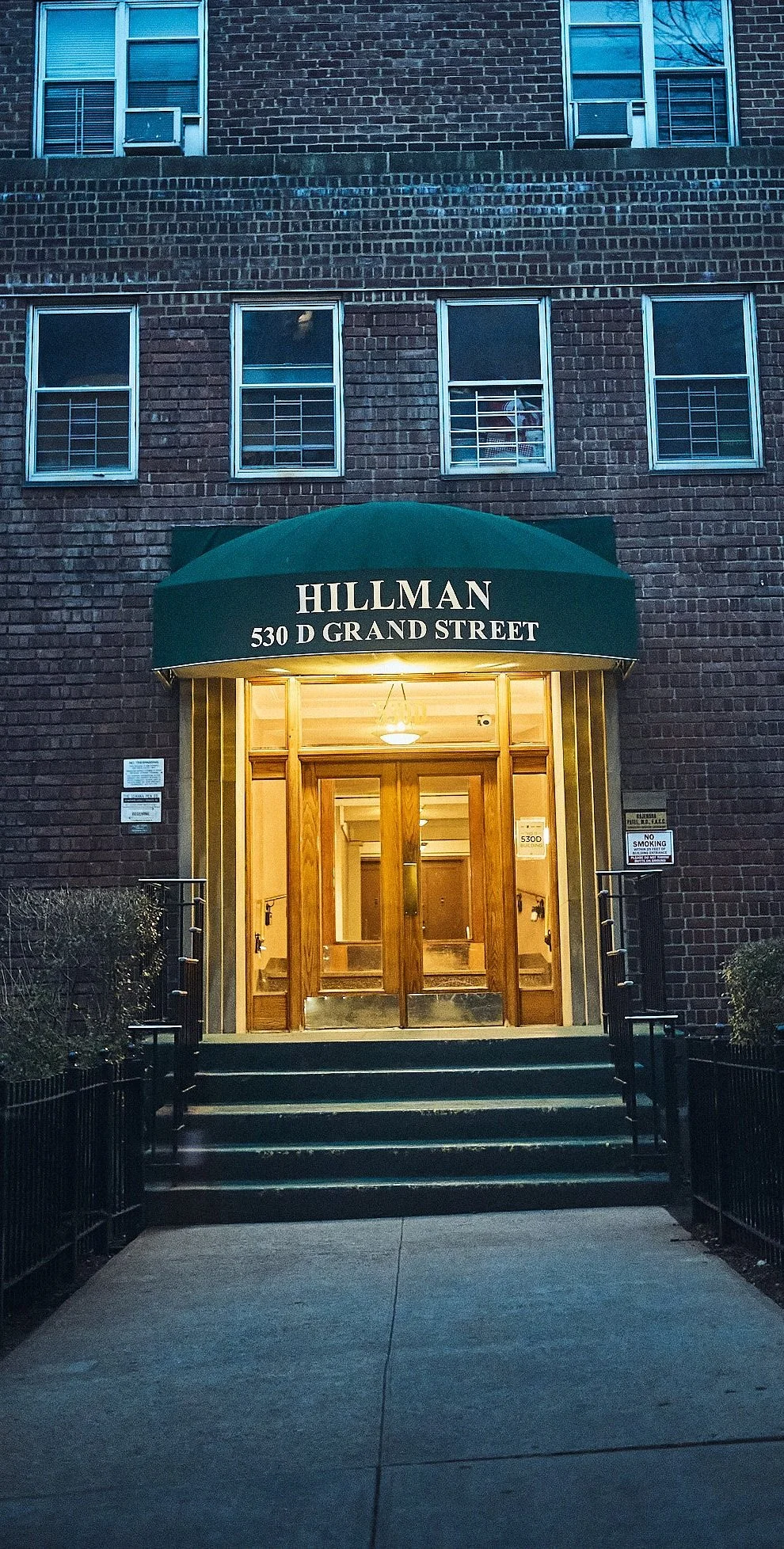 The lit door of a building entrance at dusk