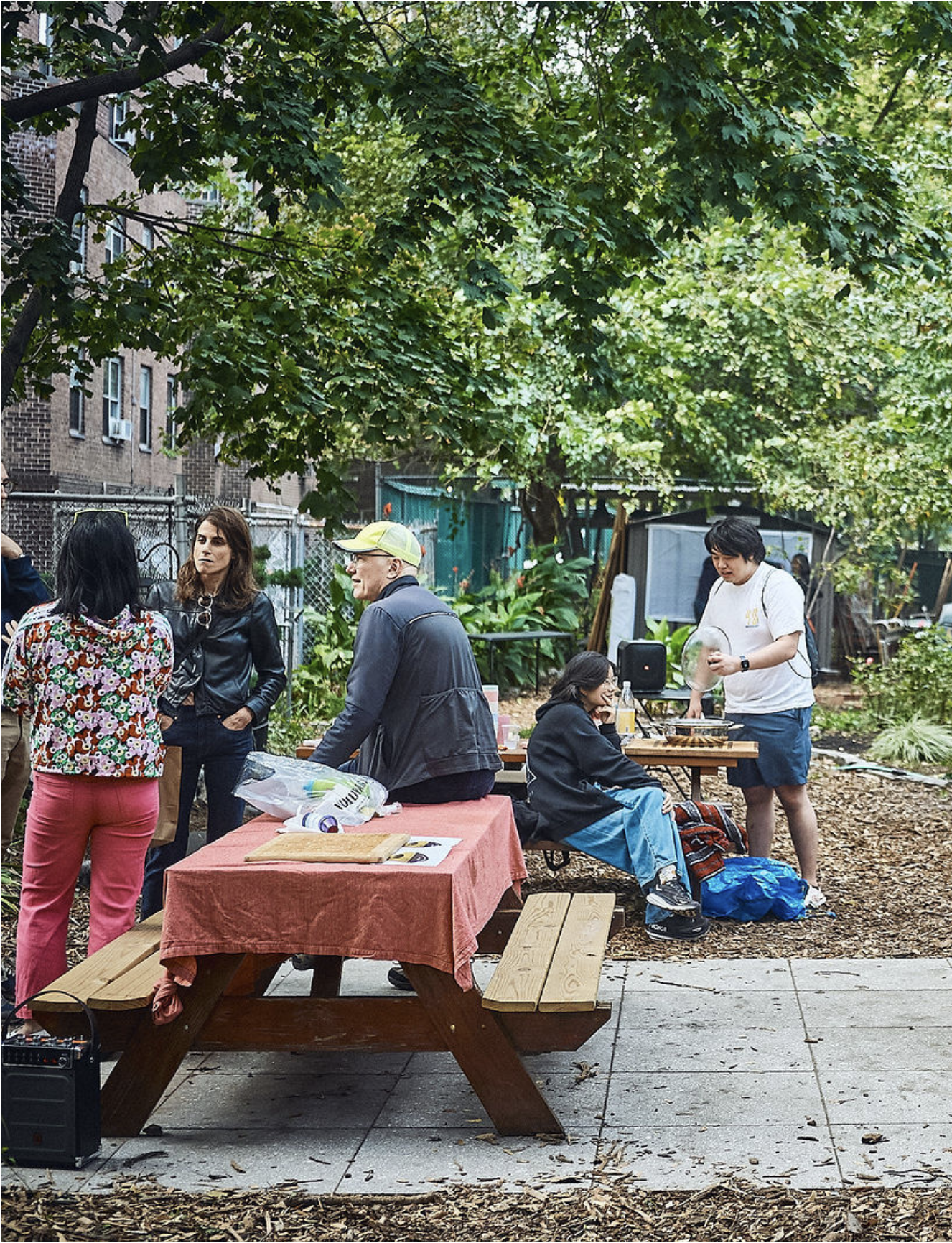 A group of people sitting near and standing near a picnic table at a community gathering