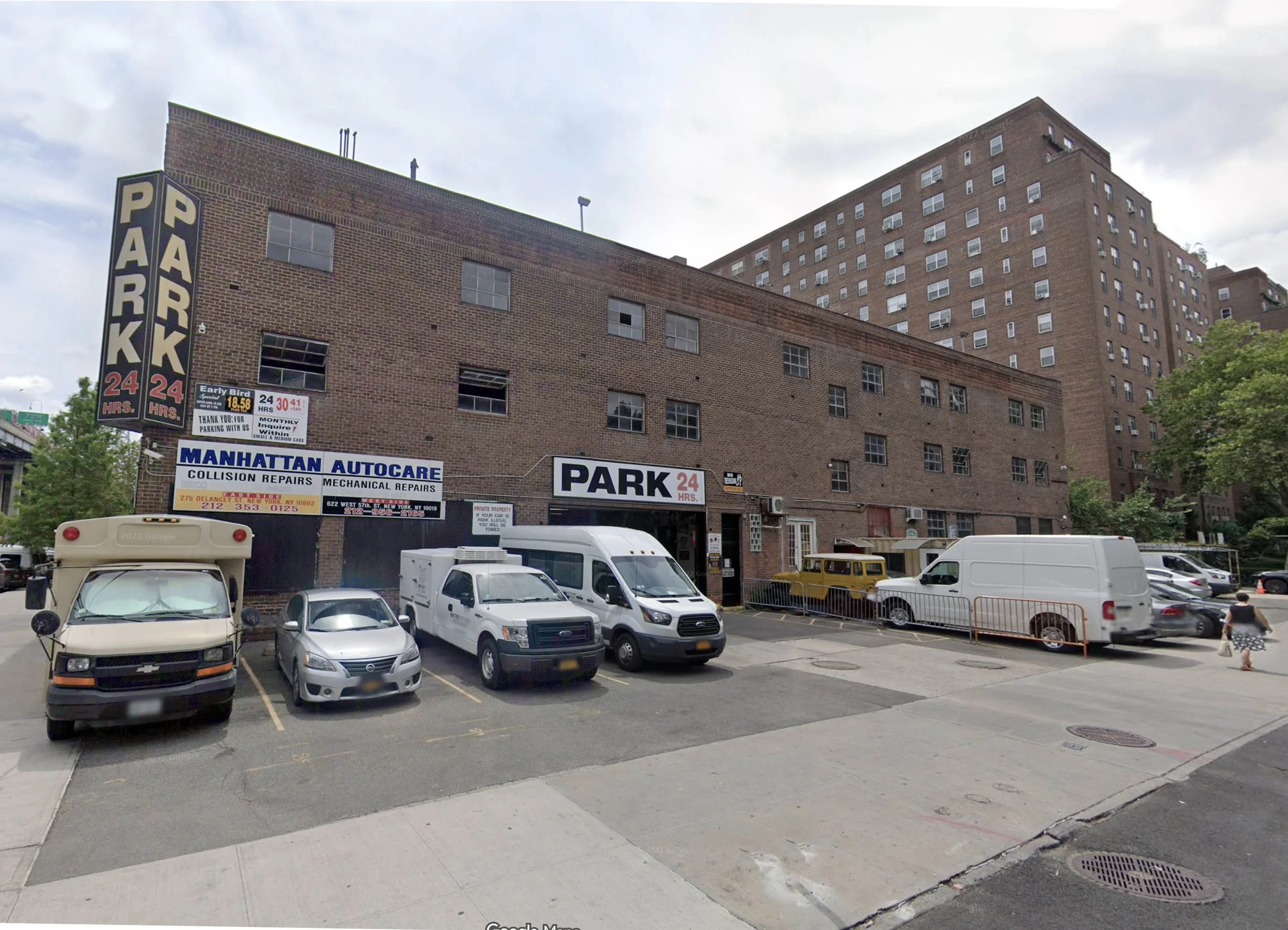 The exterior of a parking garage building with parked trucks and cars