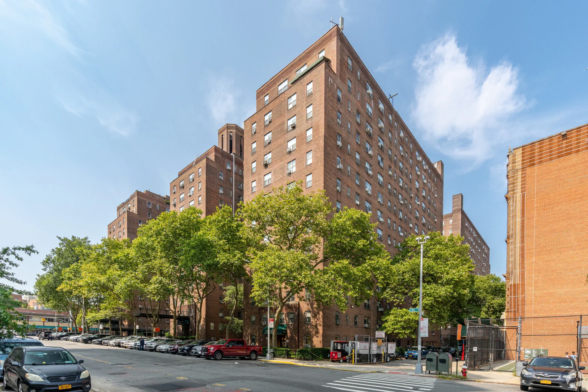 A street view of tall brick buildings on a tree-lined street.