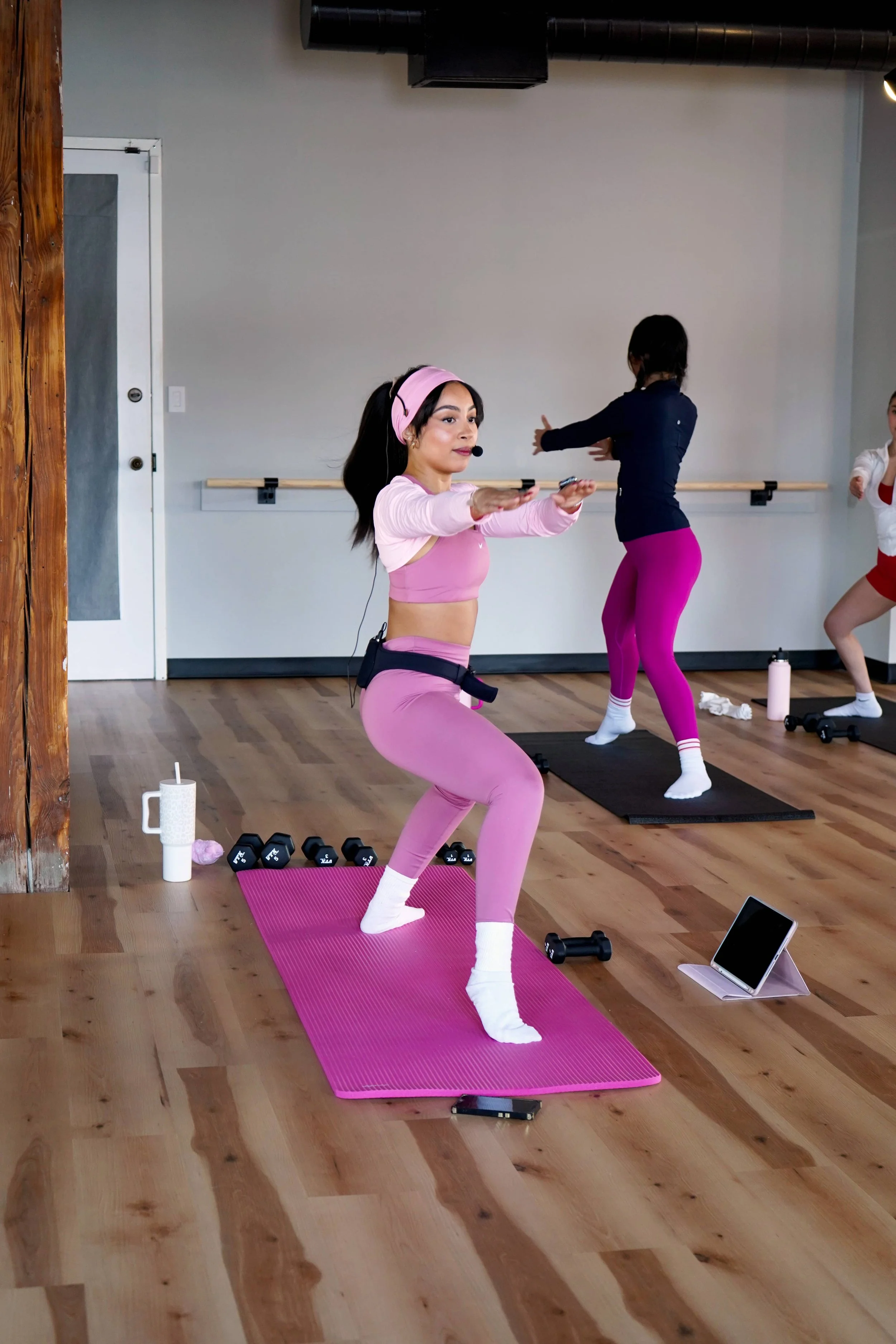 Imani Estrella leading a Pilates class in doing the warrior pose.