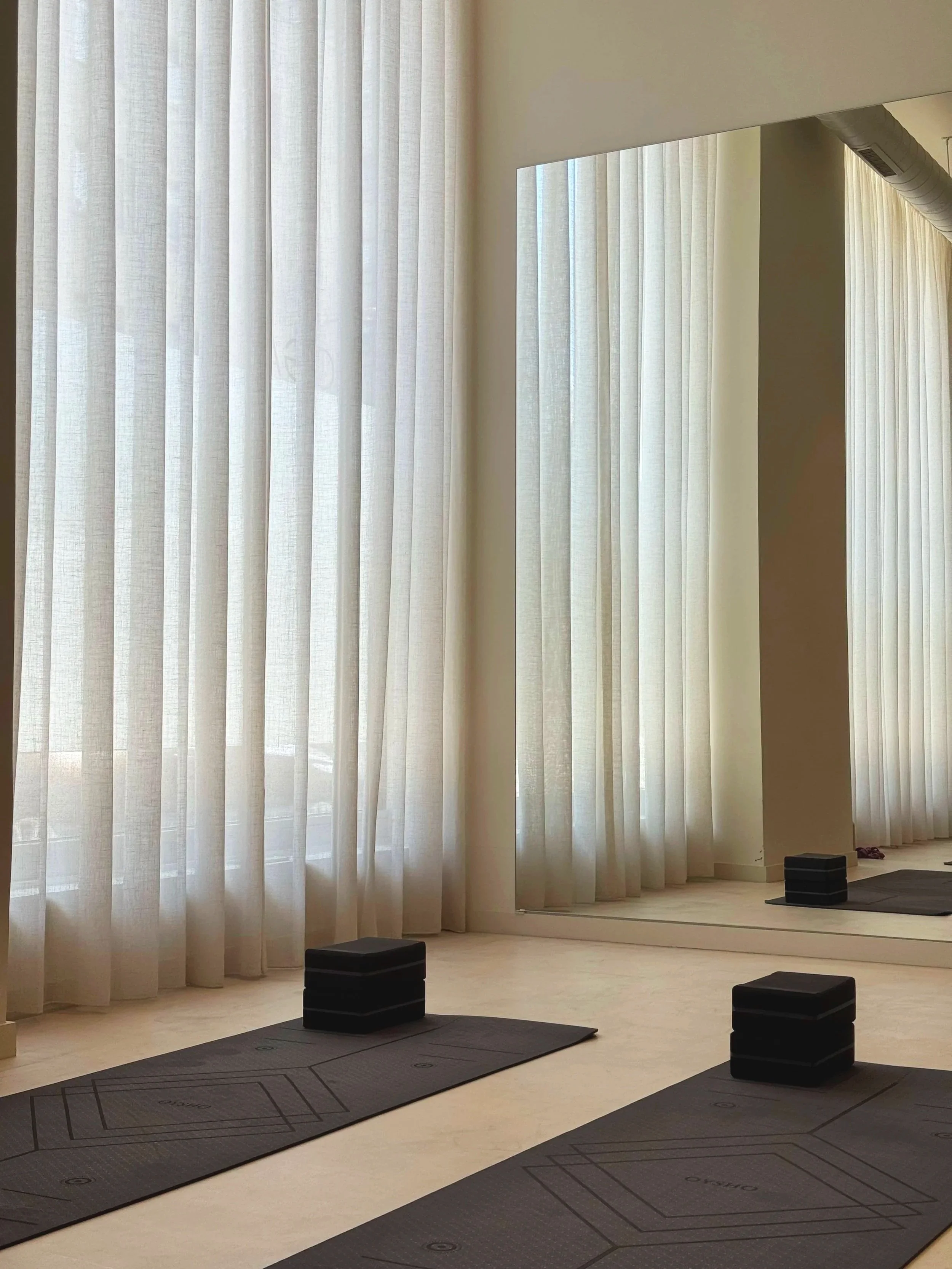 2 yoga mats with a yoga block on each, in a Pilates studio.