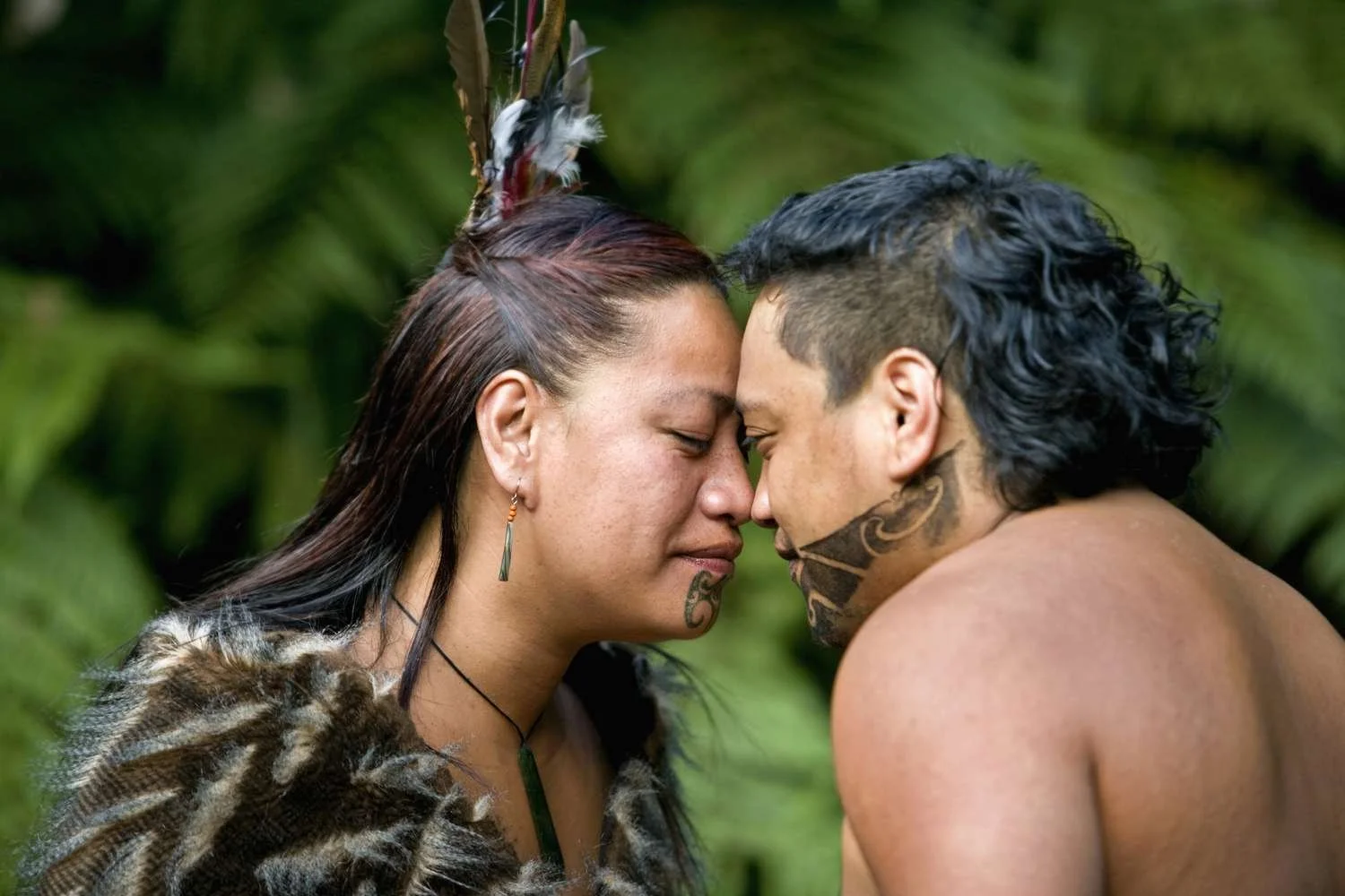 A photo showing two Māori people exchanging a hongi, a traditional greeting, by pressing their foreheads and noses together.