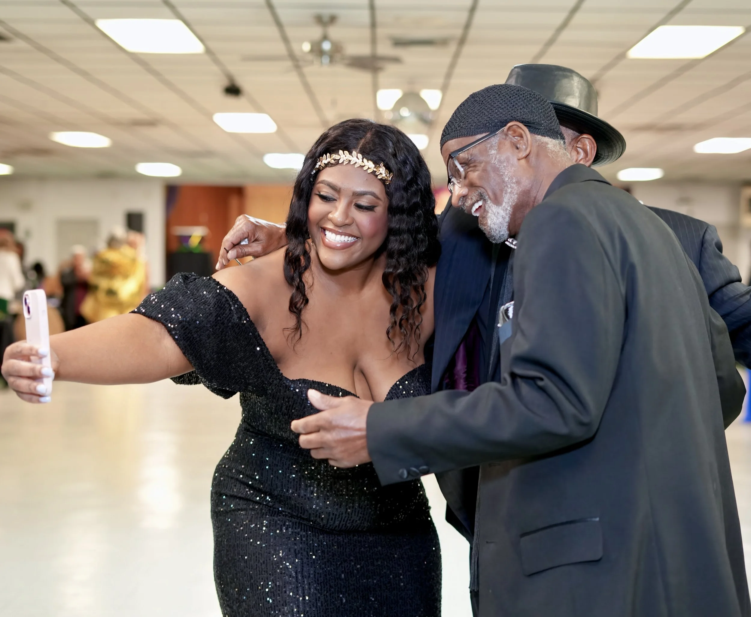 A young woman and an older man dancing together in a large room, smiling and enjoying themselves.