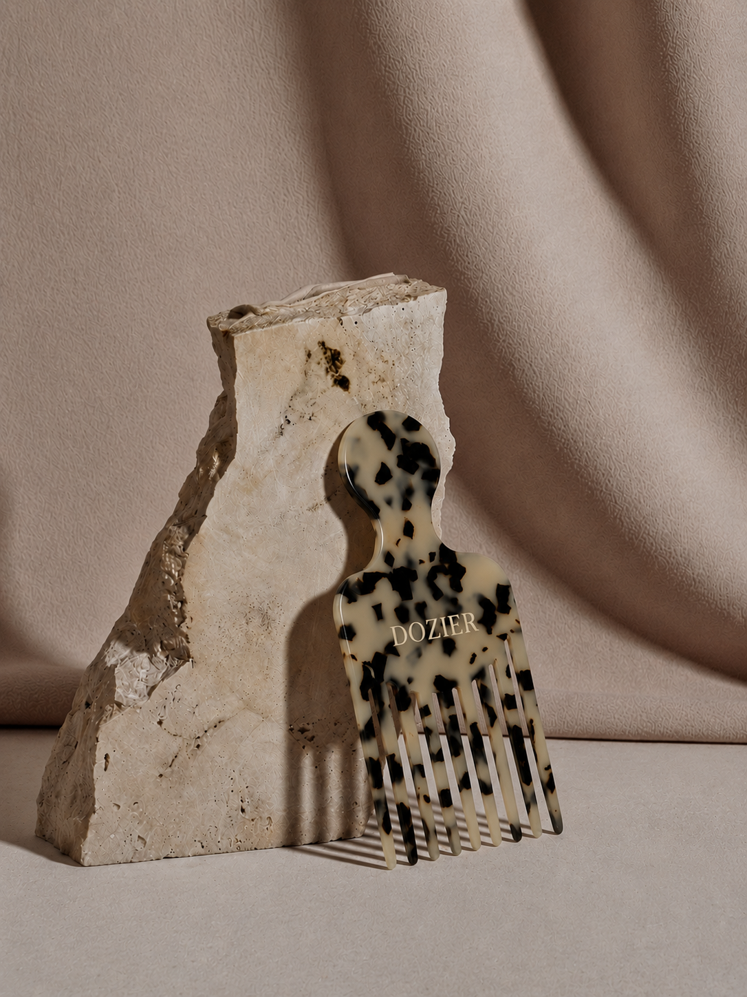 Tortoise shell hair pick leaning against travertine stone block
