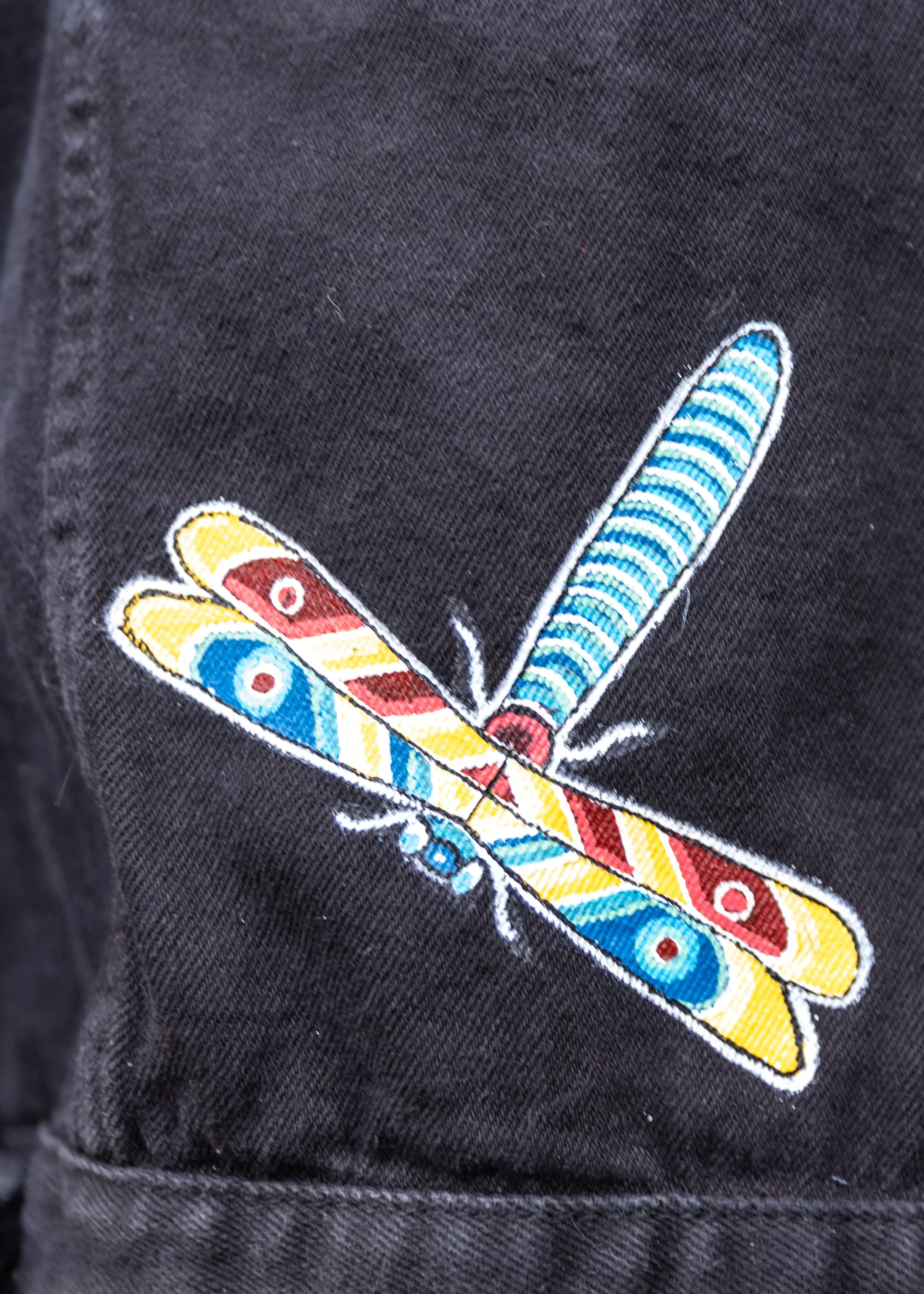 Close-up of embroidered colorful butterfly on black fabric.