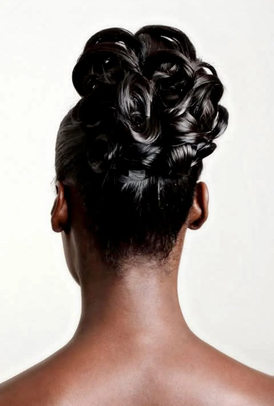 Back view of a person with dark, shiny, and styled hair in large curls.