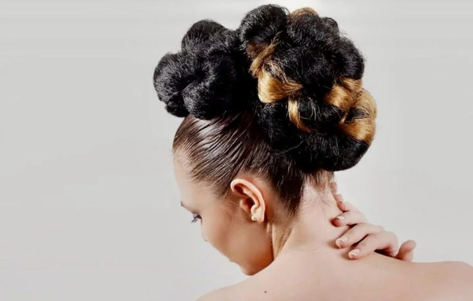 A woman with an elaborate updo hairstyle featuring large, styled curls.