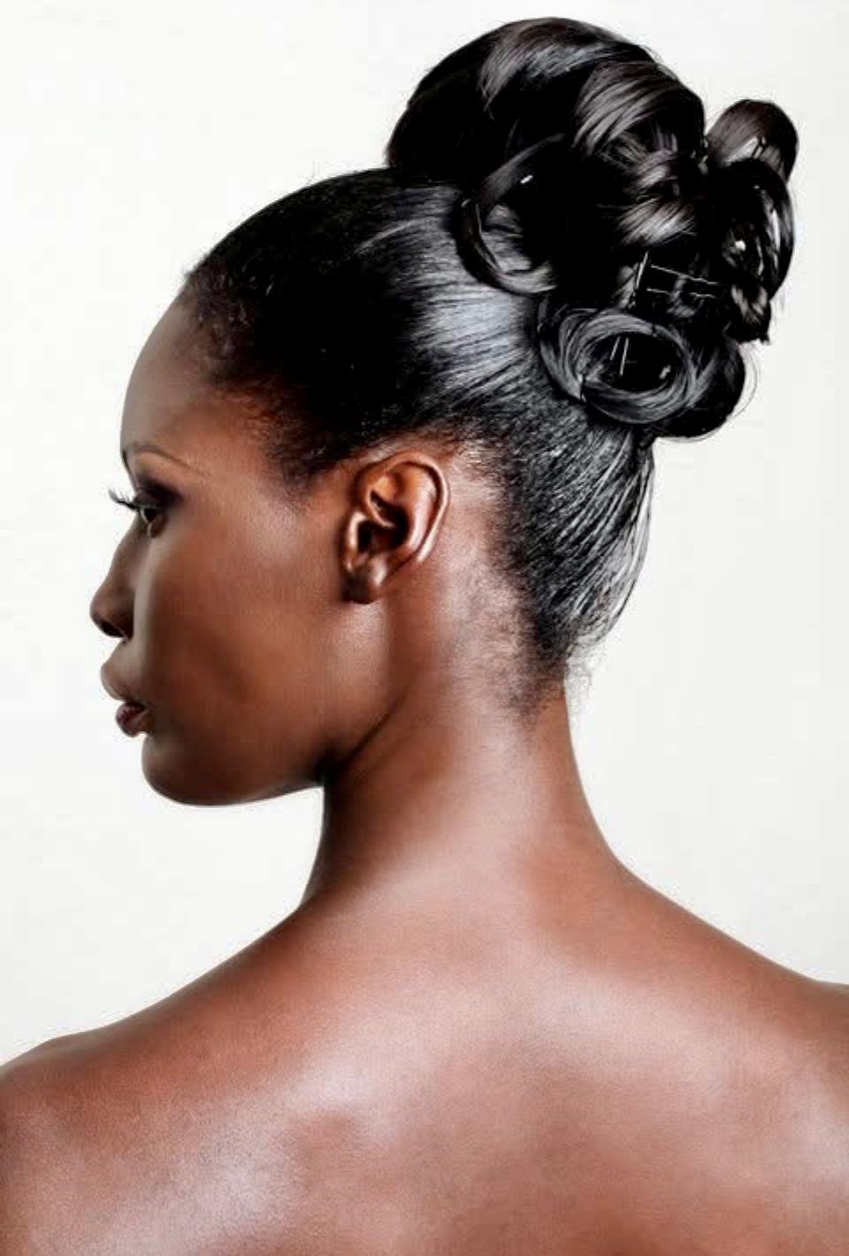 Side profile of a woman with dark skin and elegant black hair styled in intricate curled updo.