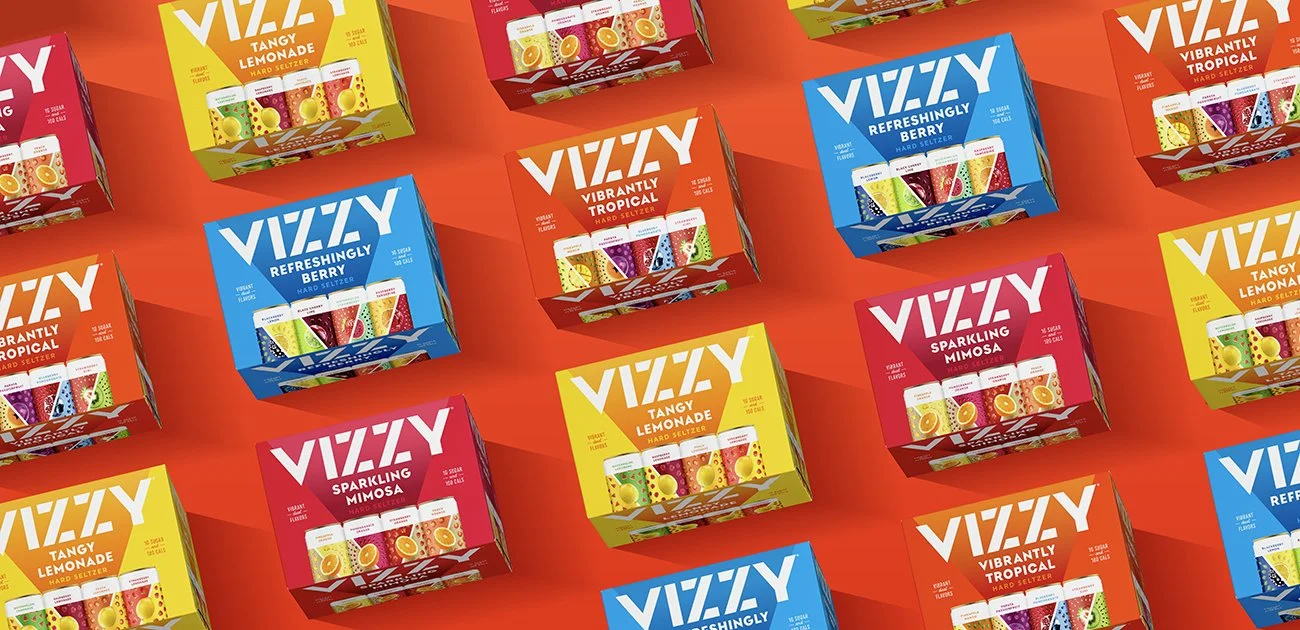 Colorful boxes of VIZZY hard seltzer products arranged on a red background, featuring flavors like Tangy Lemonade, Refreshingly Berry, Vibrantly Tropical, and Sparkling Mimoso.