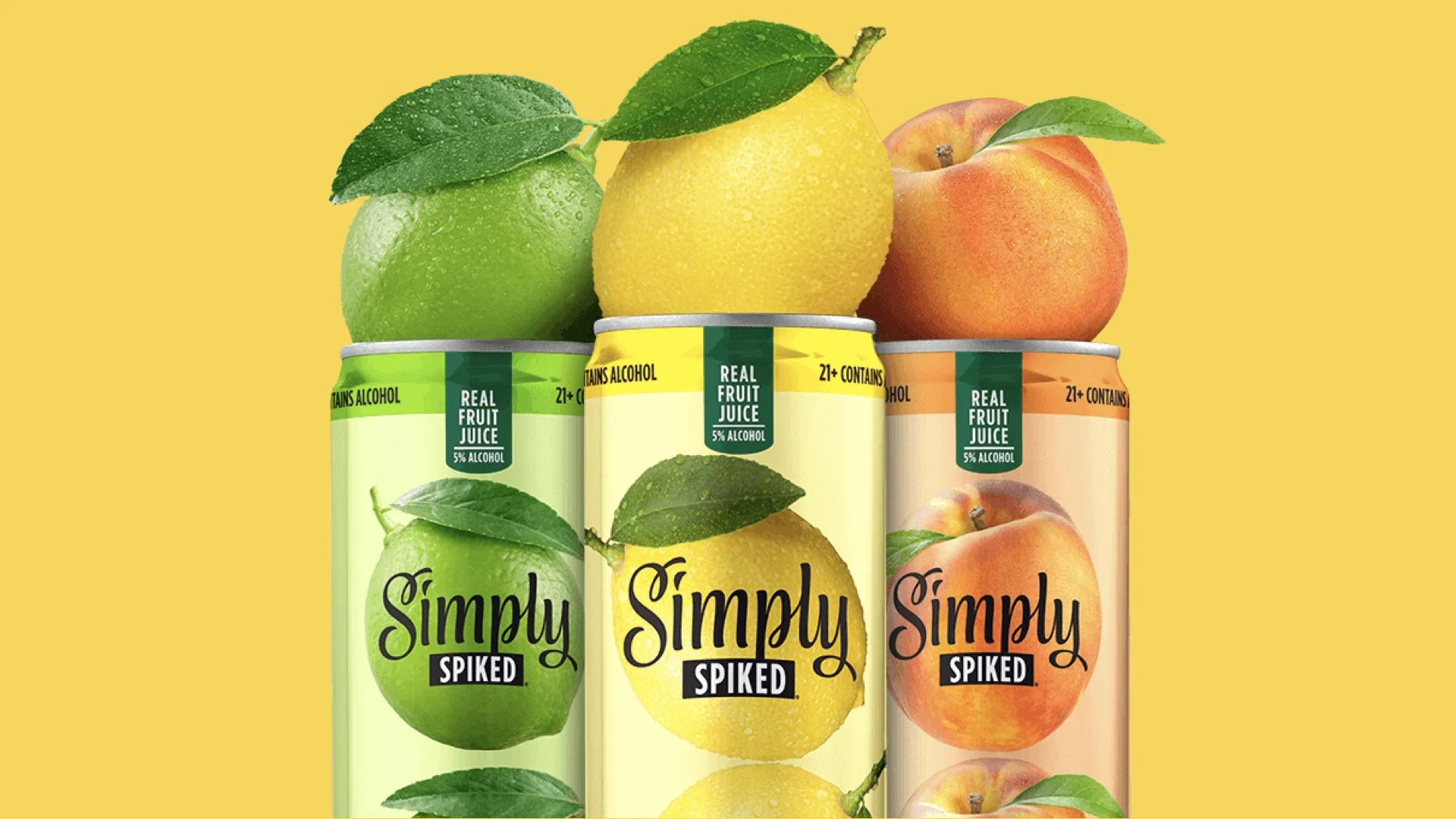 Cans of Simply spiked real fruit juice with images of lime, lemon, and peach on a yellow background