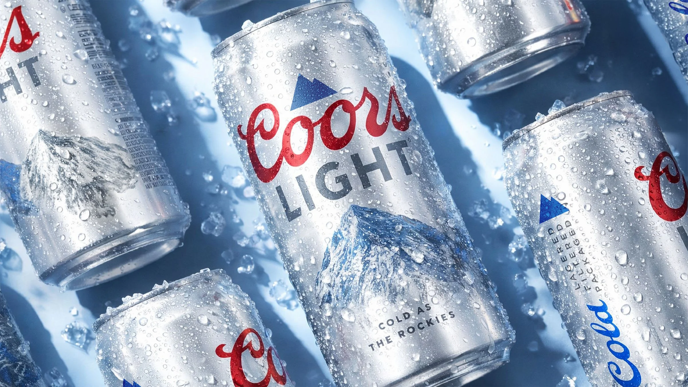 Multiple cans of Coors Light beer with condensation, lying on a wet surface.