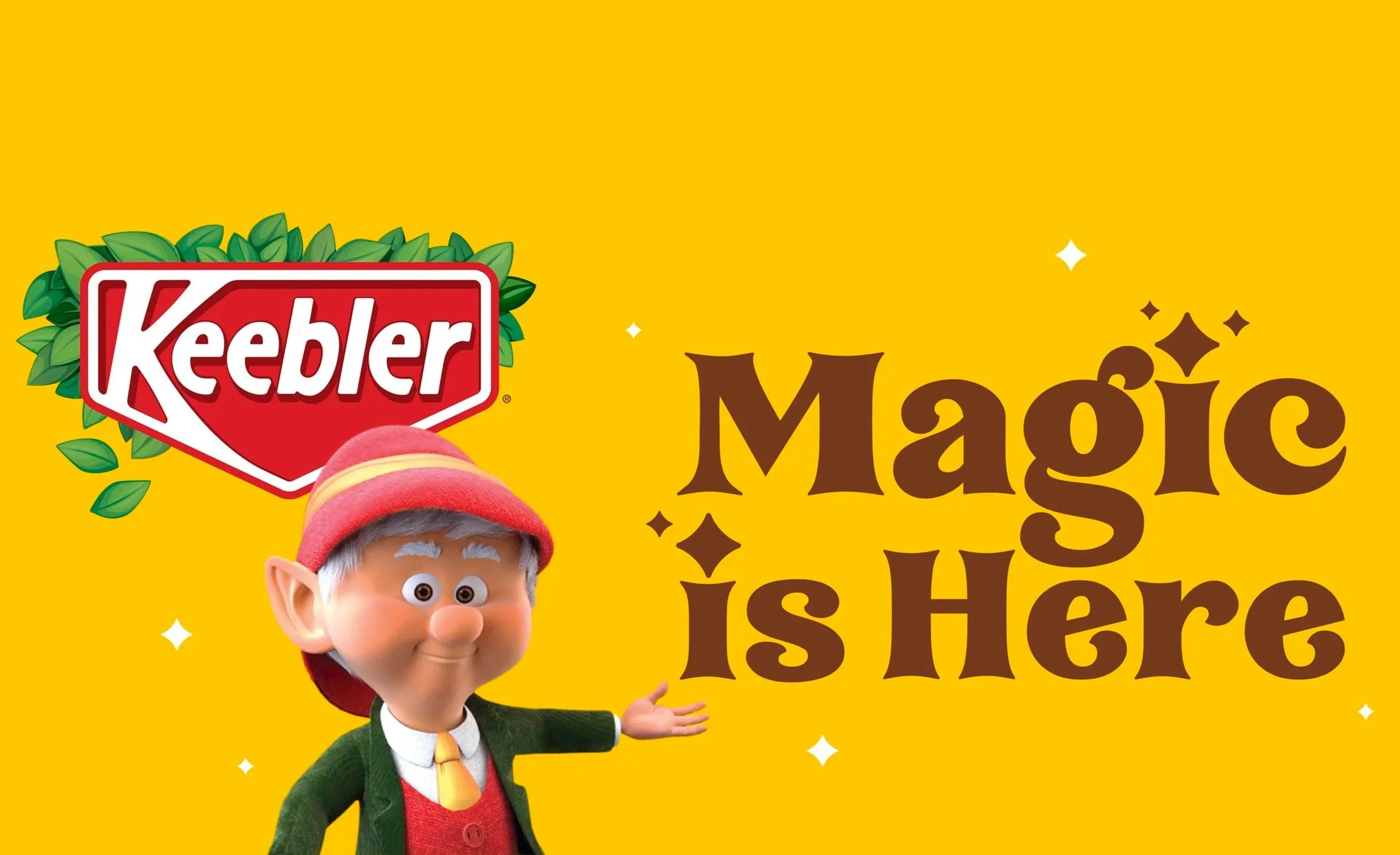 Part of a bright yellow background with the red and white Keebler logo, a cartoon elf with gray hair, a red elf hat, green jacket, yellow shirt, and red vest, and text that reads 'More Magic Is Here' with some decorative sparkles.