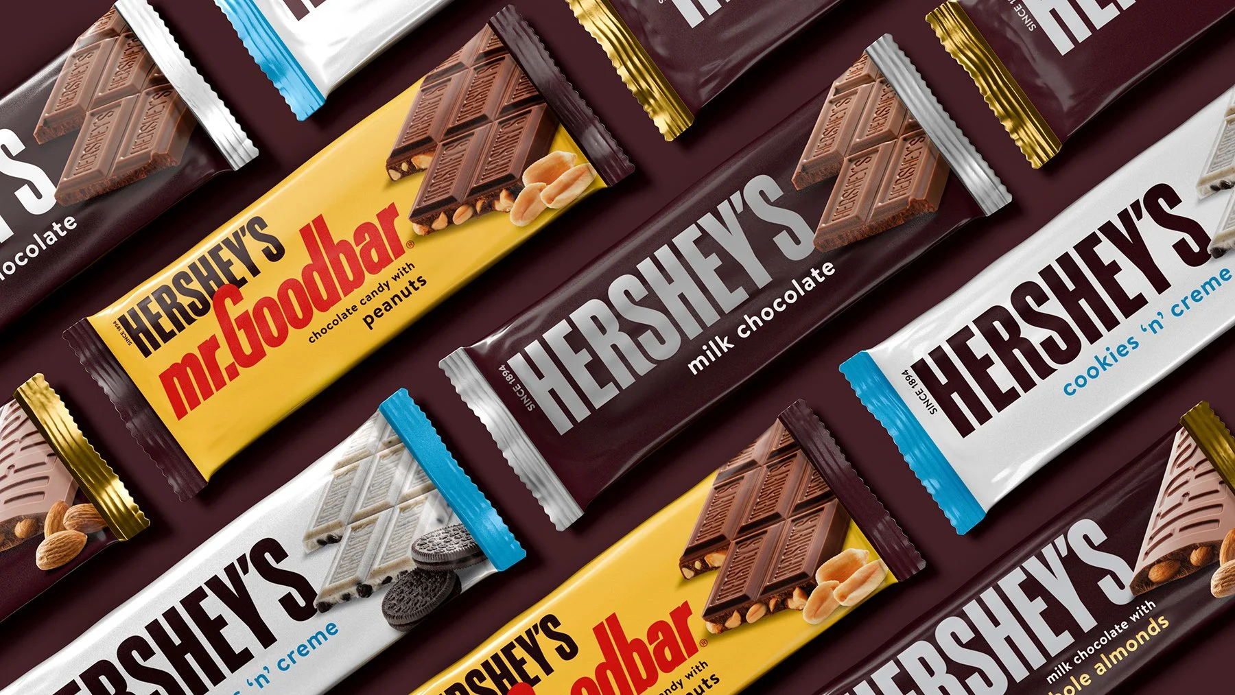 Multiple Hershey's chocolate bars with different flavors, including milk chocolate, mr. goodbar with peanuts, and cookies 'n' creme, arranged on a surface.