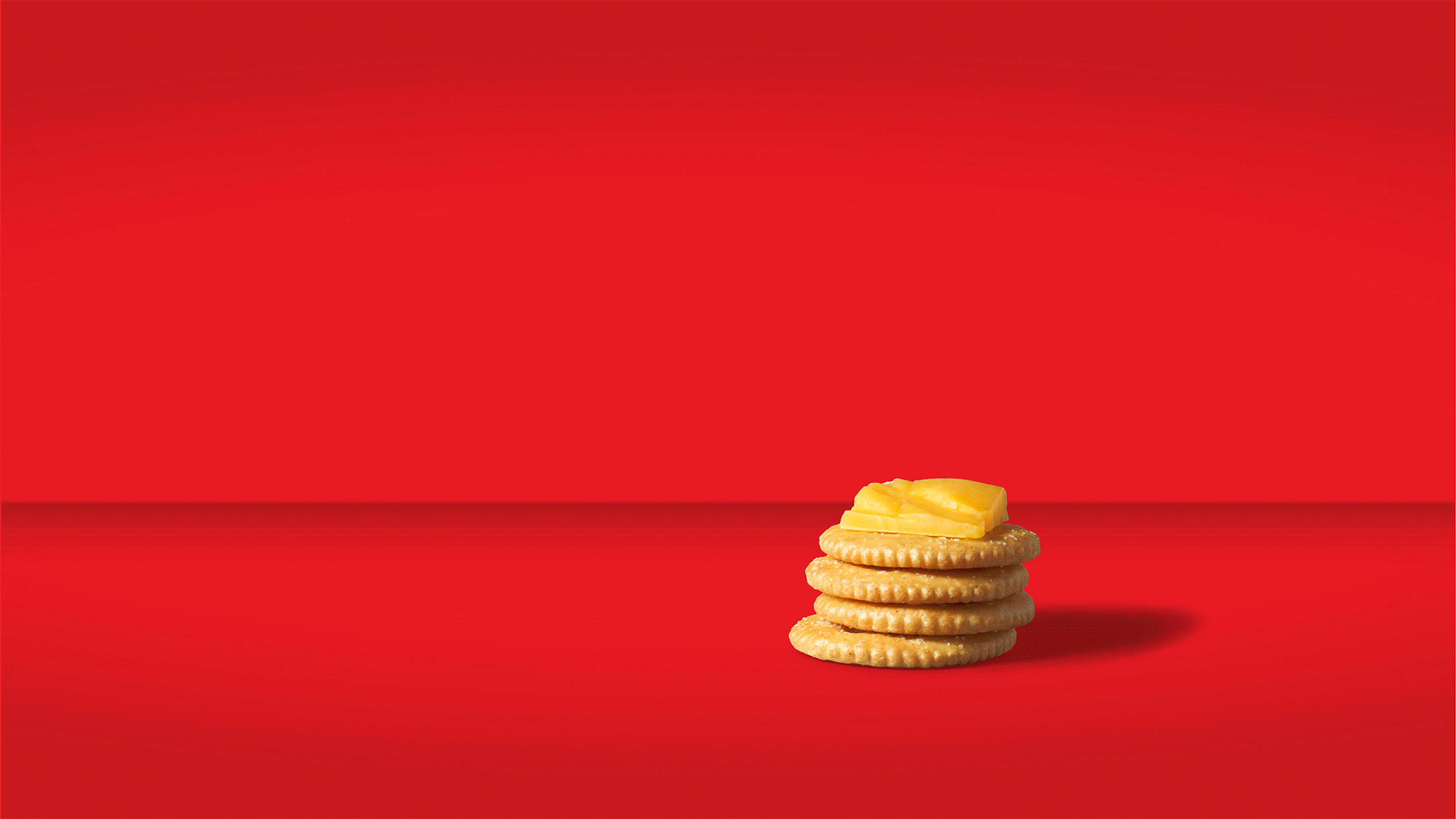 Ritz brand logo by Soulsight agency. Stack of plain cookies topped with a piece of cheese on a red background.