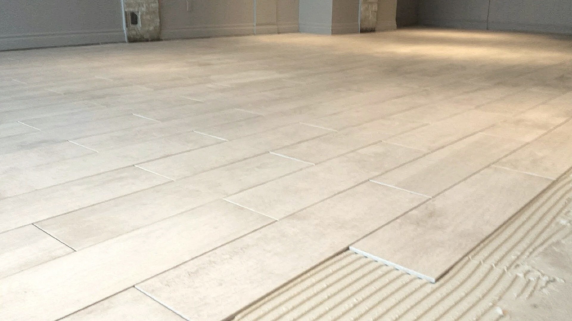 Close-up view of beige tiled floor with a tactile paving strip at the edge.