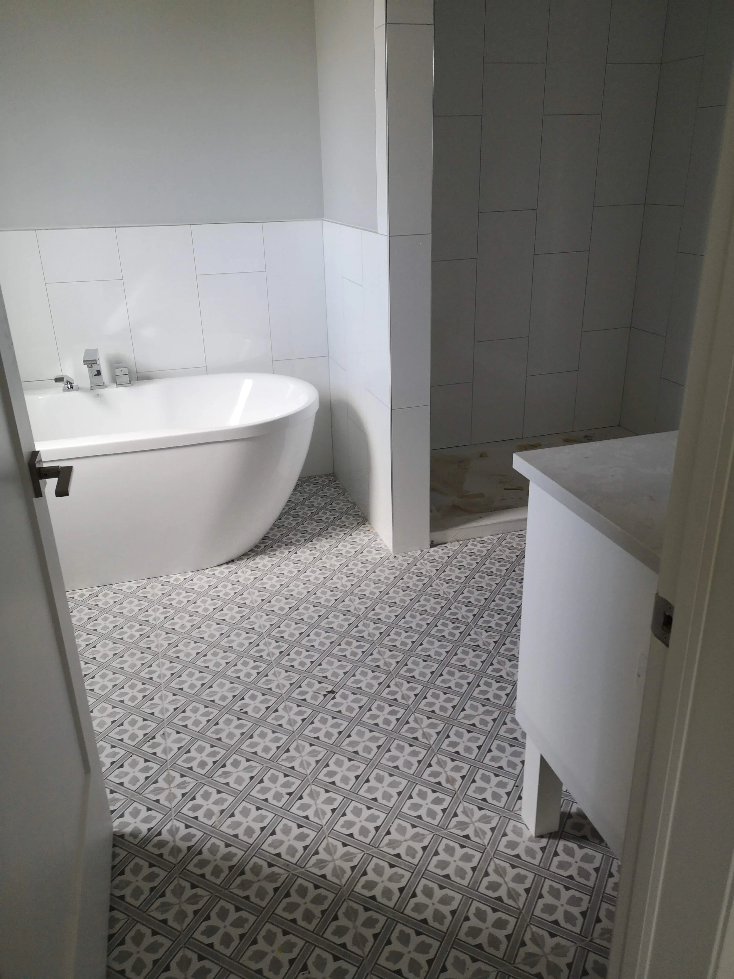 A modern bathroom with a freestanding bathtub, a tiled shower area, and a white vanity or cabinet.