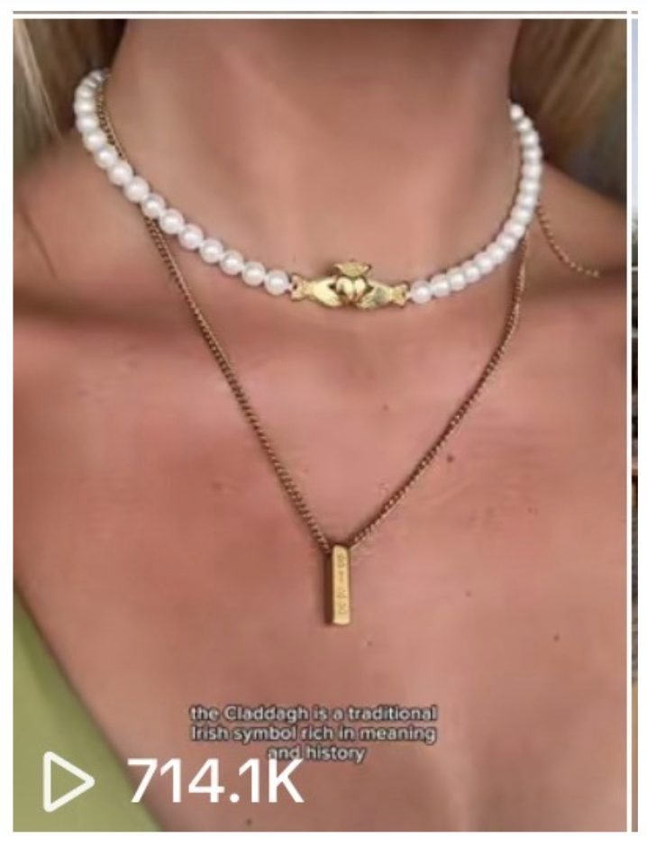 A person wearing two necklaces: a white pearl choker with a gold clasp and a gold chain with a rectangular pendant.