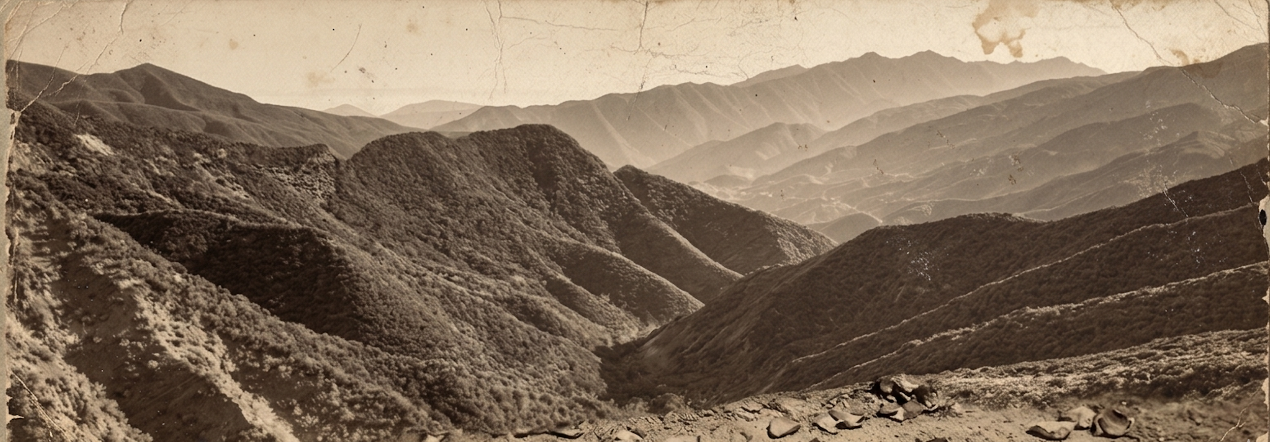 Sepia-toned photograph of Ojai's Los Padres mountains with dense vegetation, multiple layers of ridges fading into the distance, and visible cracks and tears in the photograph.