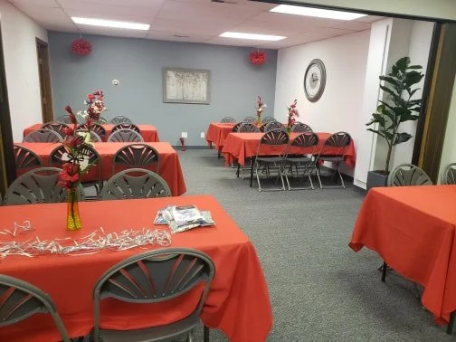 A room decorated for a celebration with tables covered in red tablecloths.