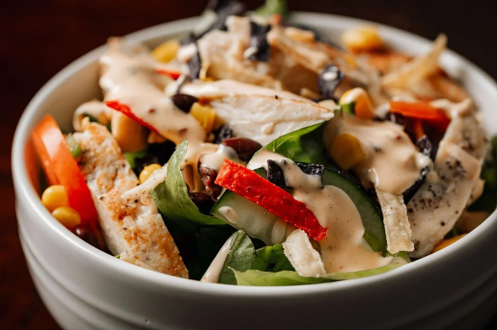 A bowl of Southwest Grilled Chicken Salad with fresh vegetables, corn, and creamy Southwest Chipotle Dressing.