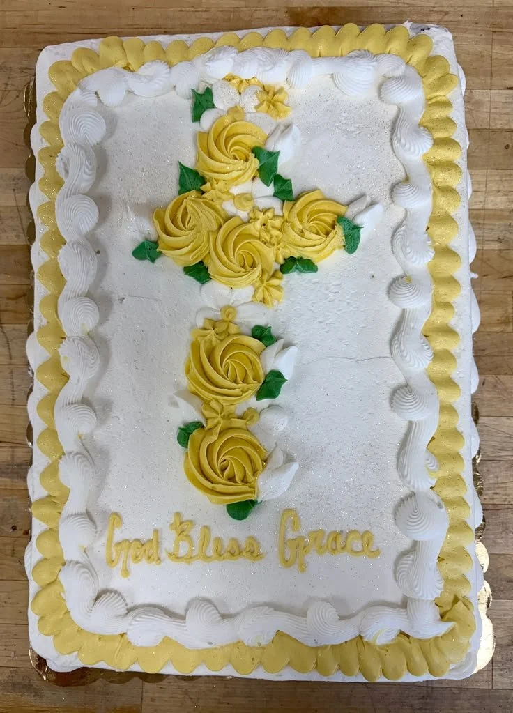 Large rectangular cake decorated with white and yellow frosting, with a message that reads 'God Bless Grace' at the bottom.