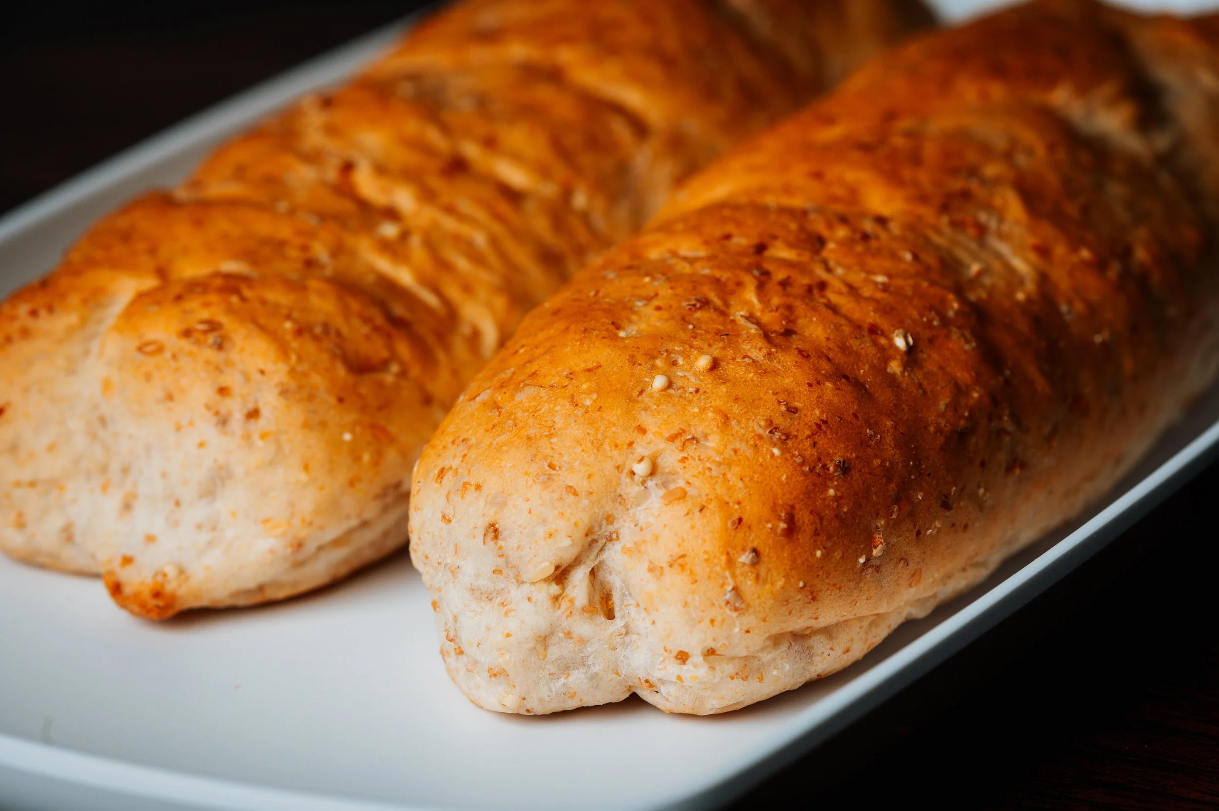 Close-up of two seasoned bread loaves on a white dish.