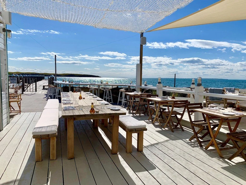 waterfront dining restaurant with wooden tables and benches outdoors