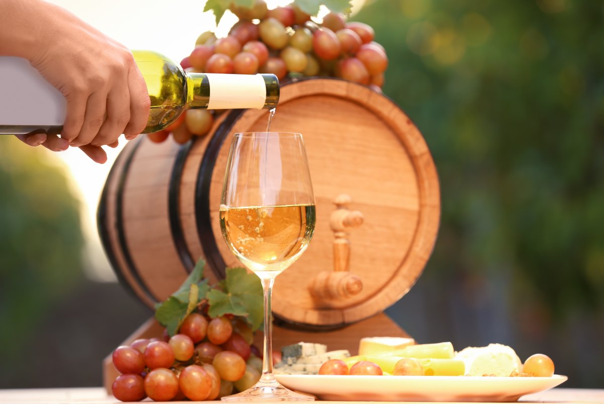 Woman pouring white wine into glass on table outdoors