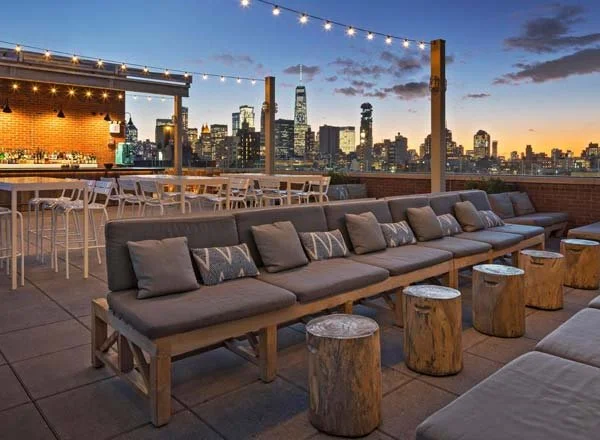 Mr. Purple rooftop in Manhattan featuring lounge seating, string lights, and skyline views at sunset in a relaxed yet upscale setting