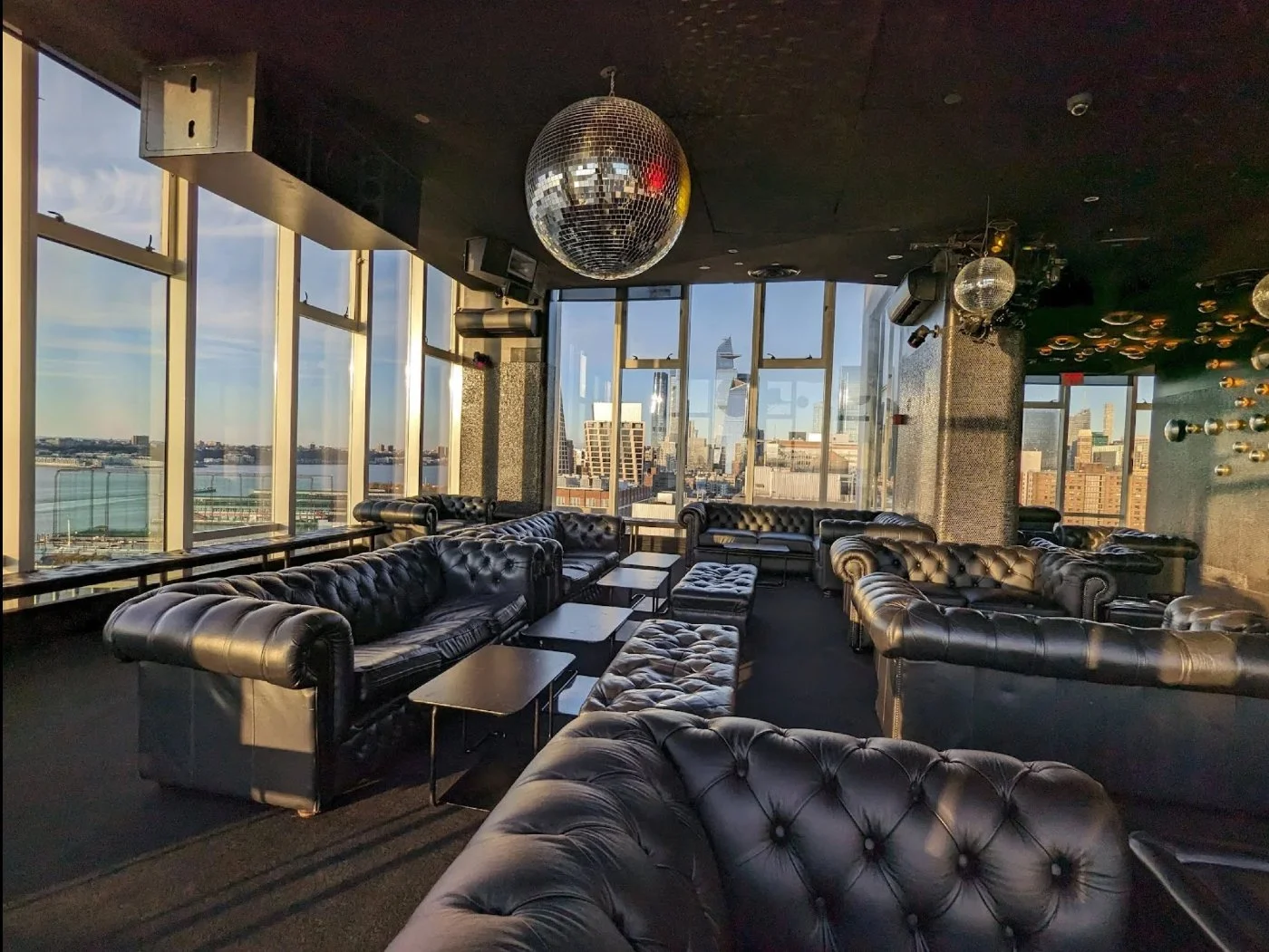 Le Bain at The Standard Hotel in NYC featuring a rooftop lounge with leather seating, disco ball, and panoramic skyline views in a stylish nightlife setting