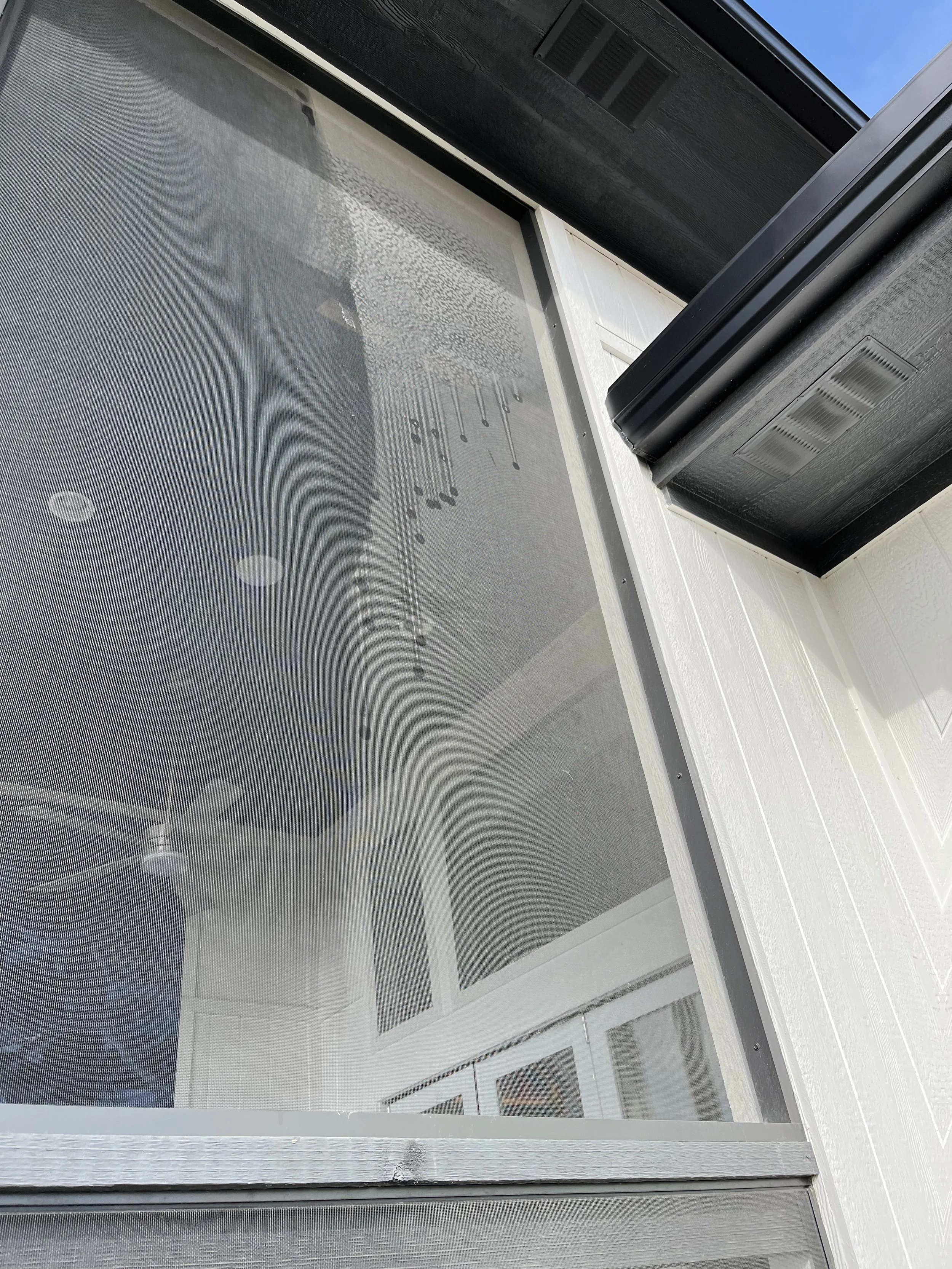 Close-up of a window with a screen and some water droplets visible on the surface.
