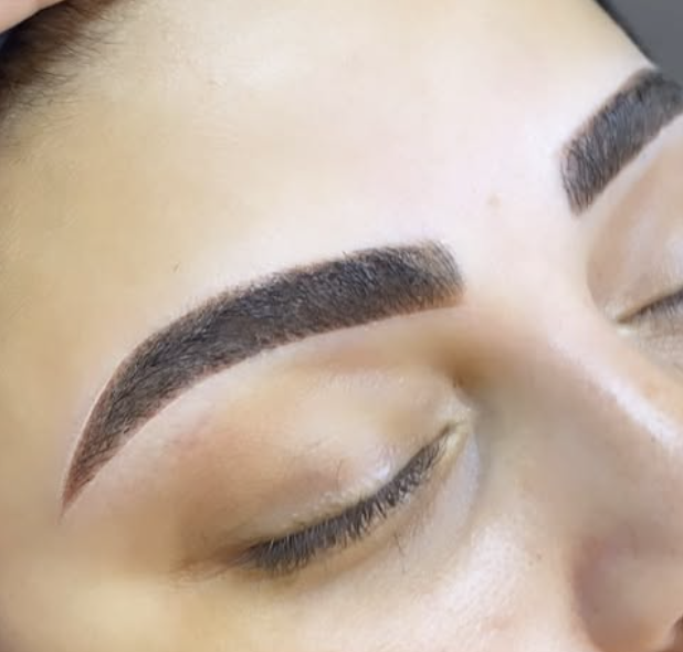 Close-up of a person's closed eye showing well-groomed eyebrows and smooth skin.