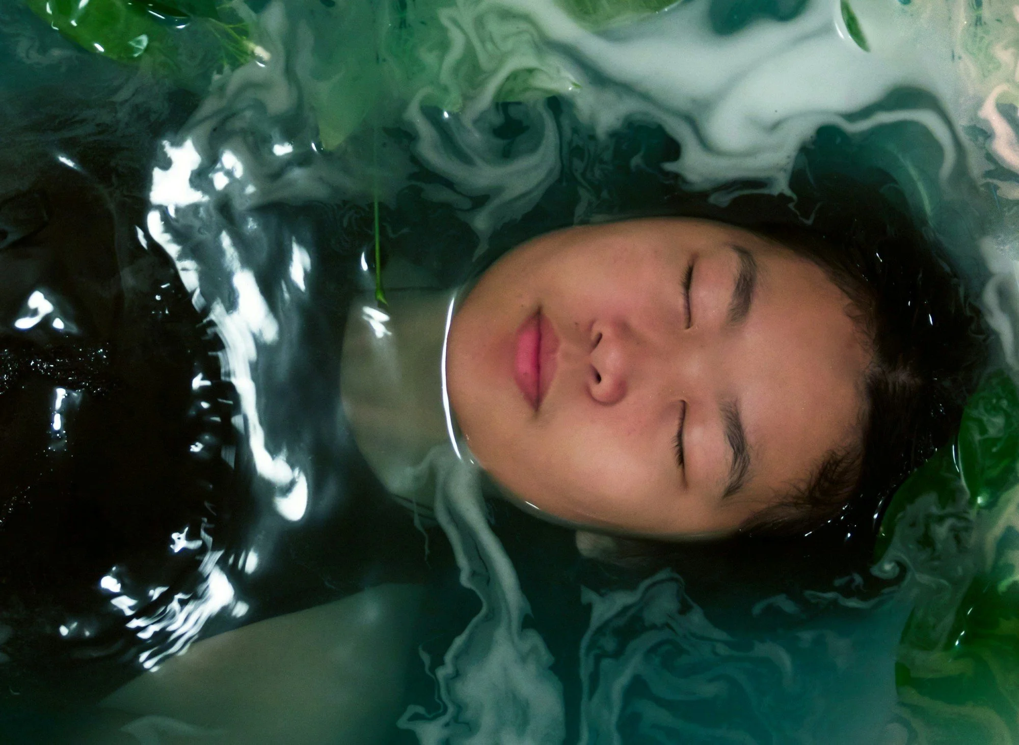 Face of a woman with her eyes closed floating on a pool