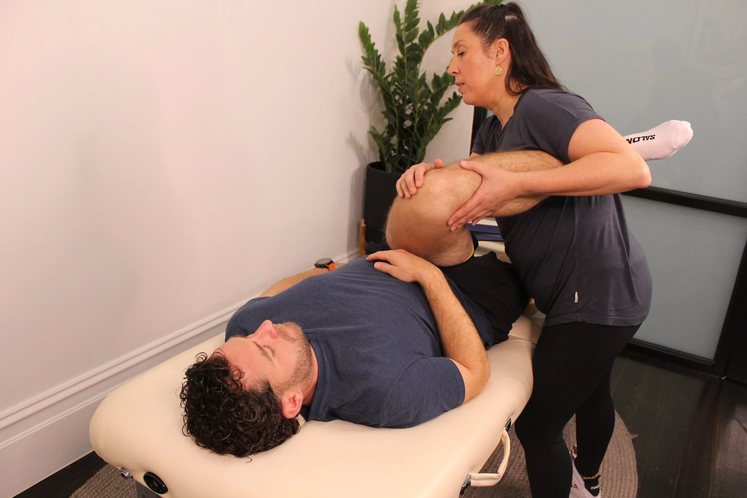 man on white massage table being stretched by a female stretch therapist
