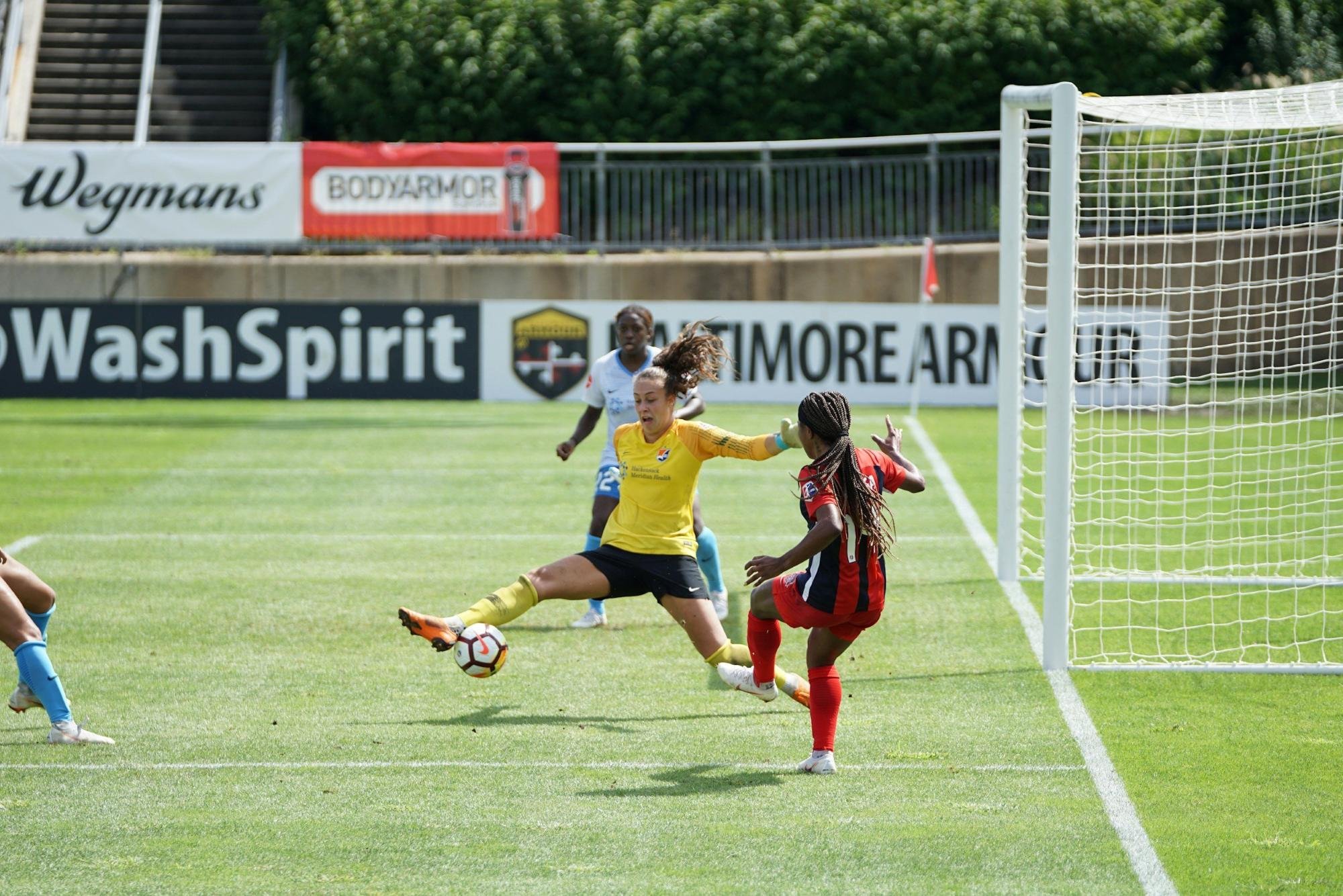Woman stretching her leg to get the soccer ball while playing against another team