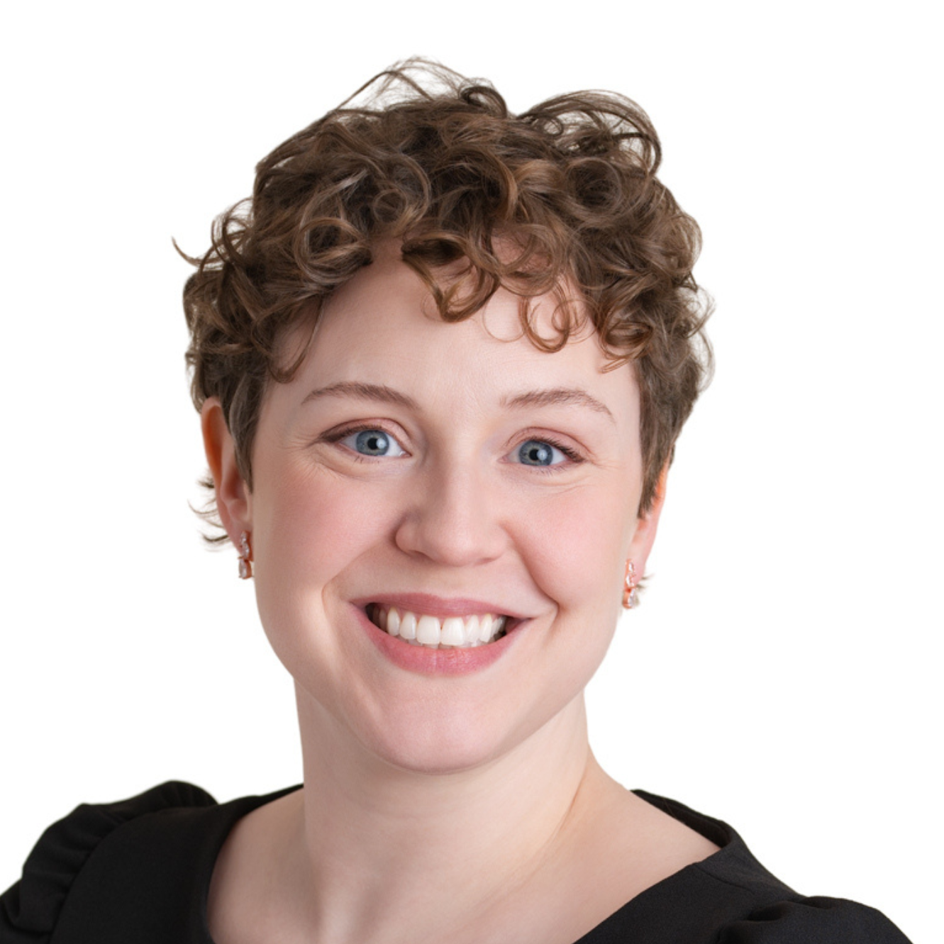 Close-up of a woman with short curly hair smiling at the camera, wearing a black top and small earrings, against a white background.