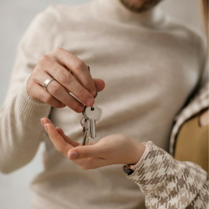 Person handing over a set of house keys to another person.