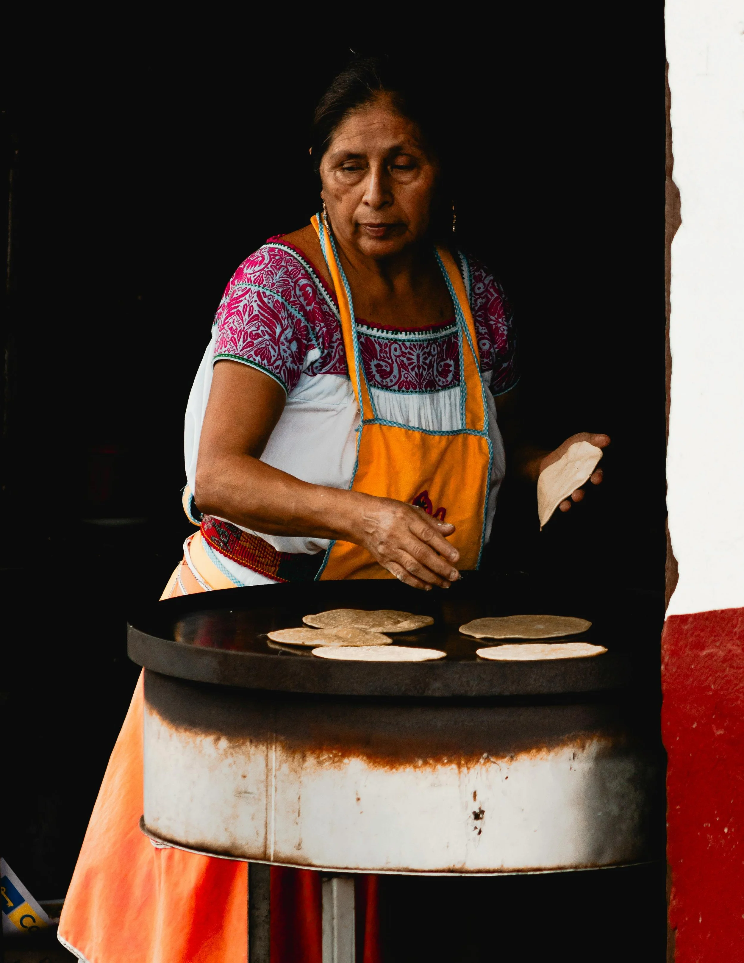 A woman cooking traditional flatbread on a large circular griddle.
