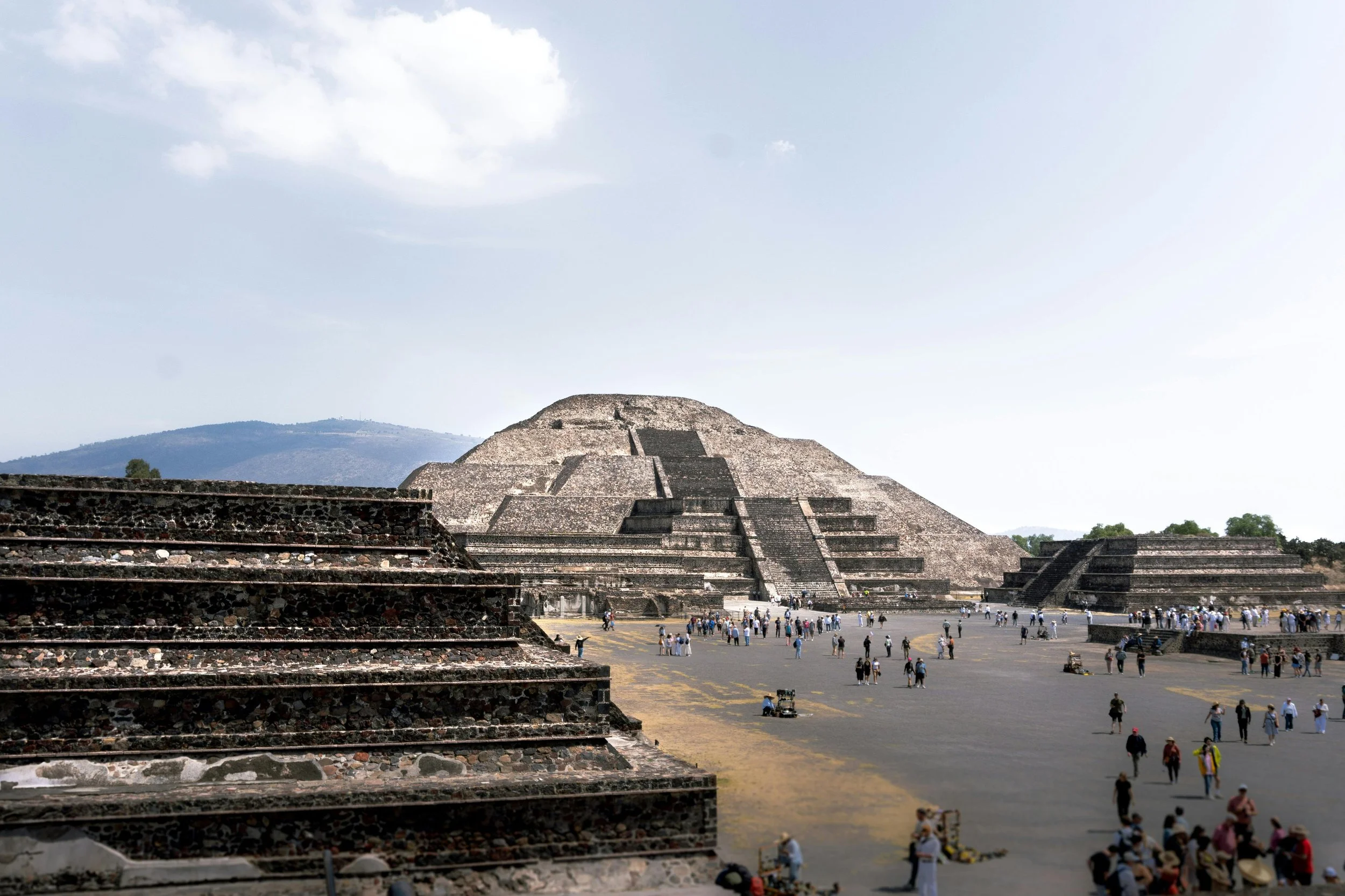 View of the ancient pyramid, Pyramid of the Magician, at Uxmal archaeological site in Mexico, with tourists walking around.