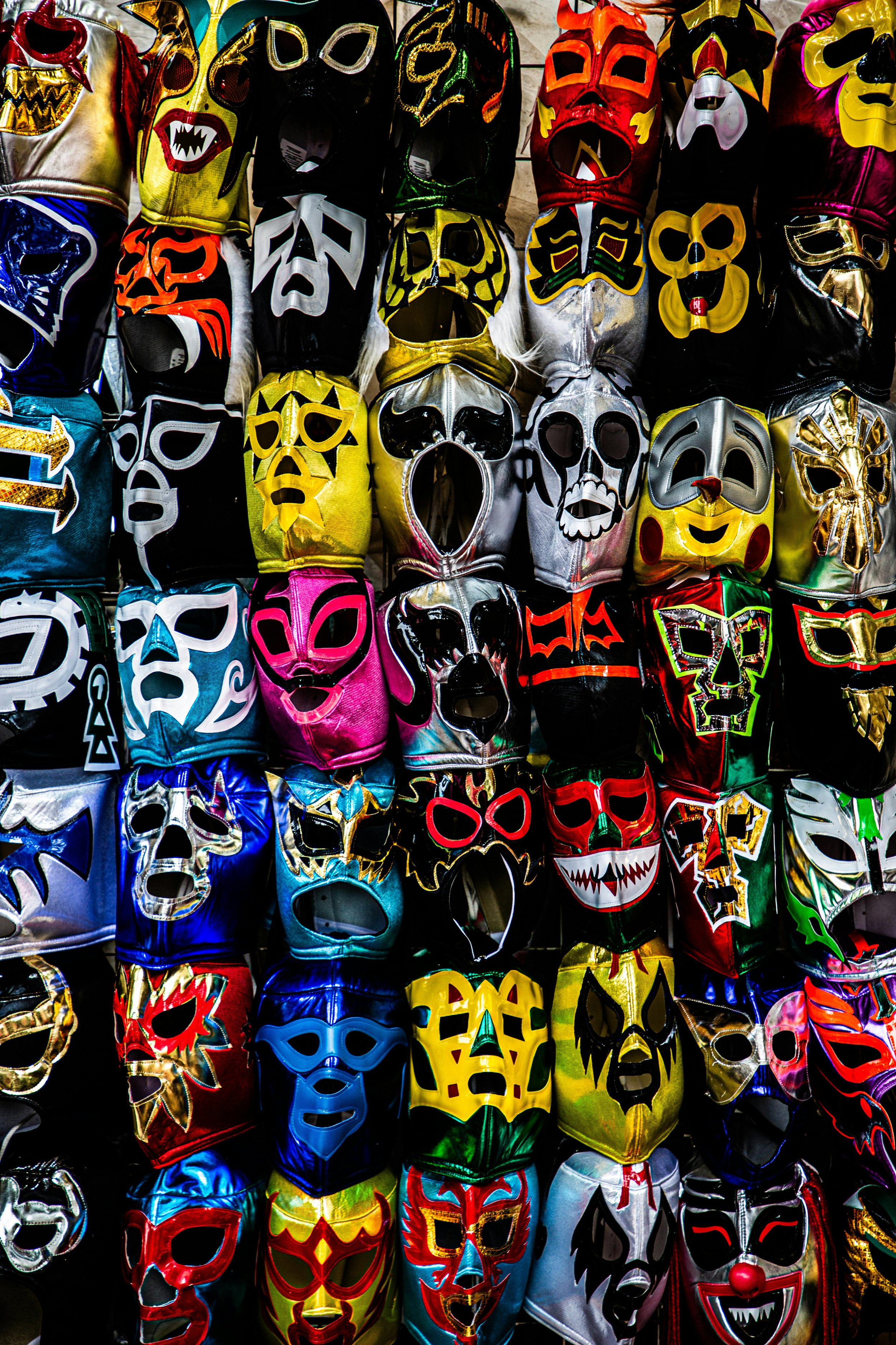 Various colorful lucha libre masks hanging on display at a market stall.