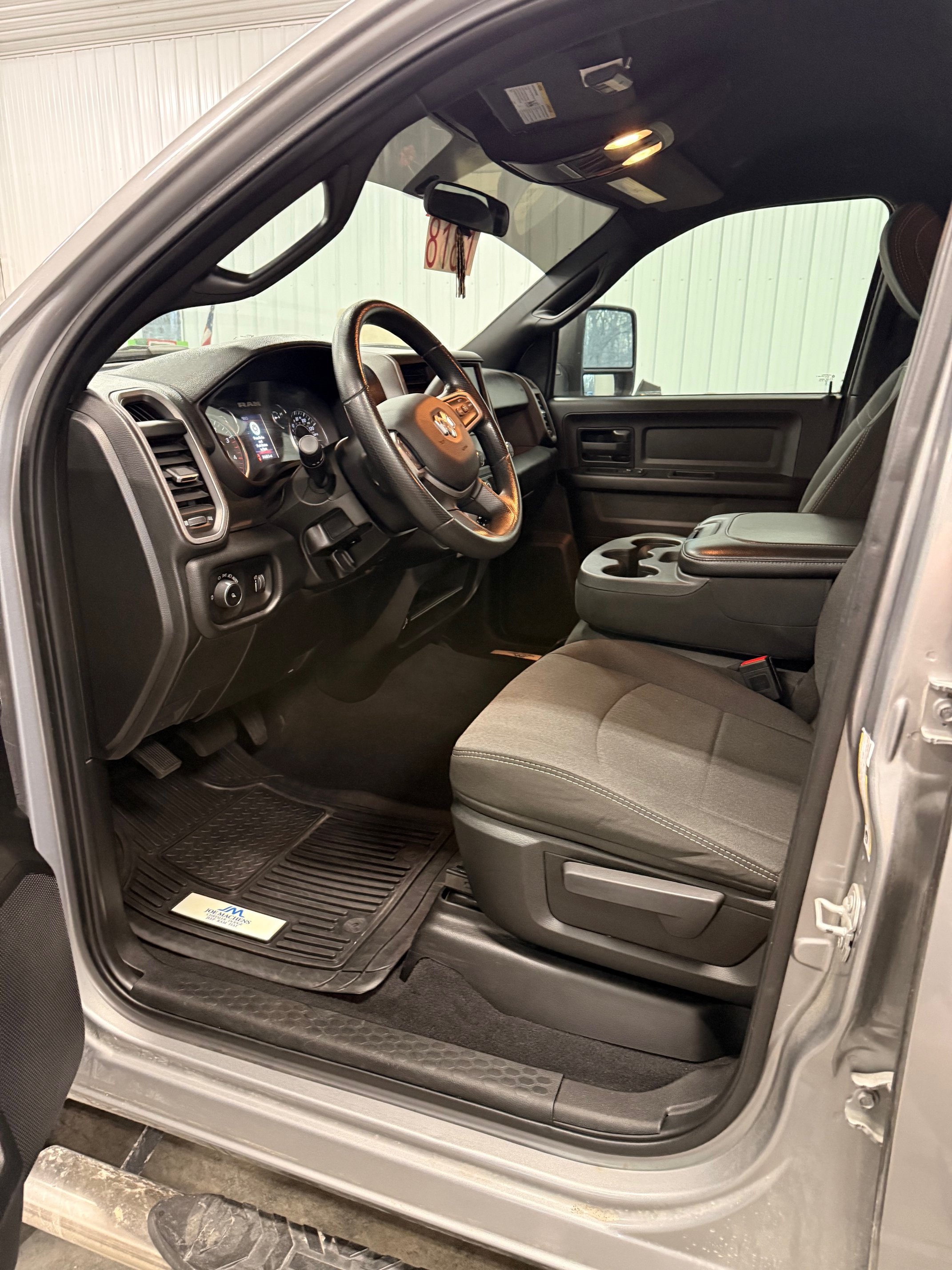 Inside view of a truck's front interior, showing the dashboard, steering wheel, driver's seat, and center console with cup holders.